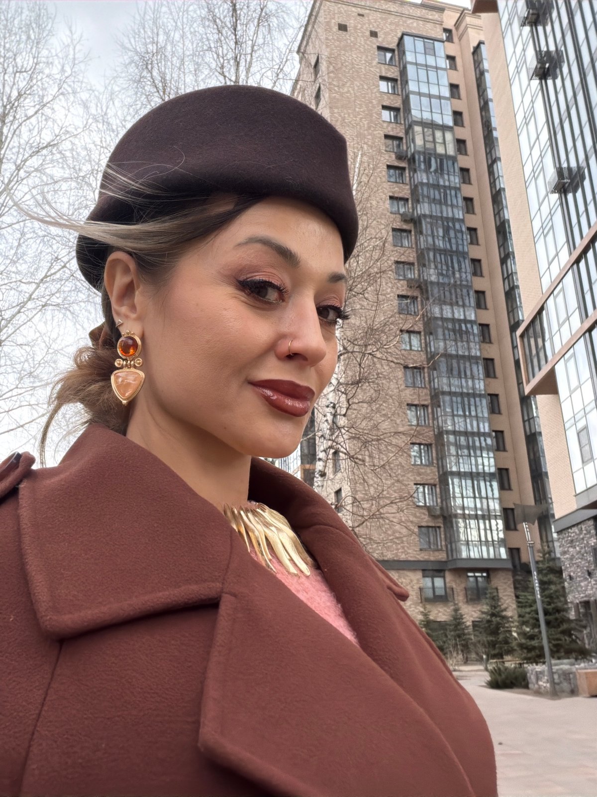 Woman in brown beret photographed outside buildings in Krasnoyarsk