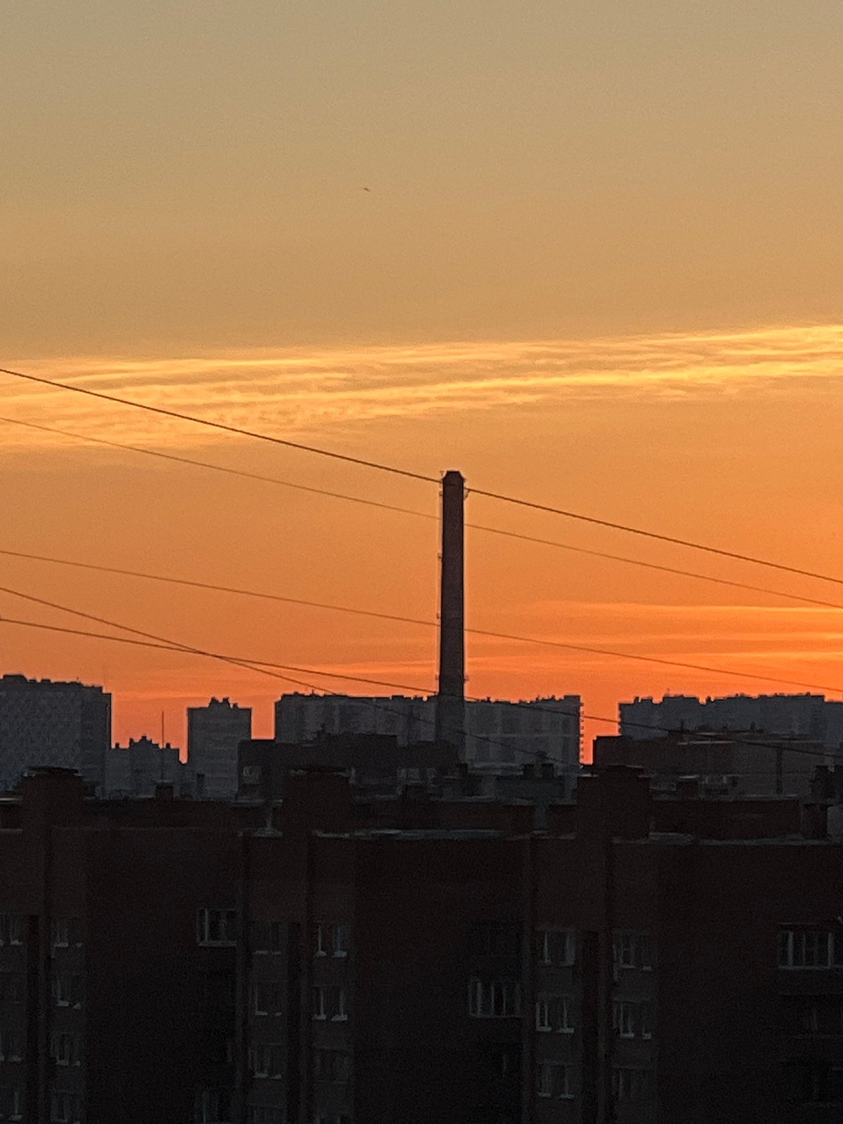 Sinyavino at golden hour: apartment blocks, chimneys, and trams