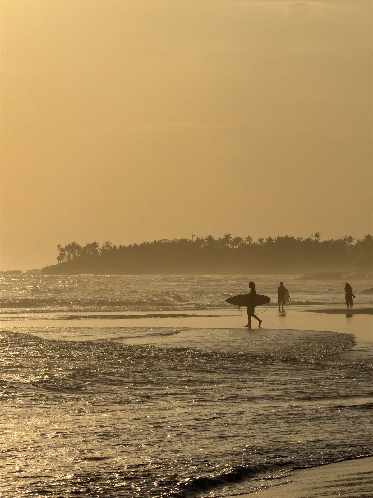 Golden hour at Bali's beaches — surfers, waders, and sunset crowds