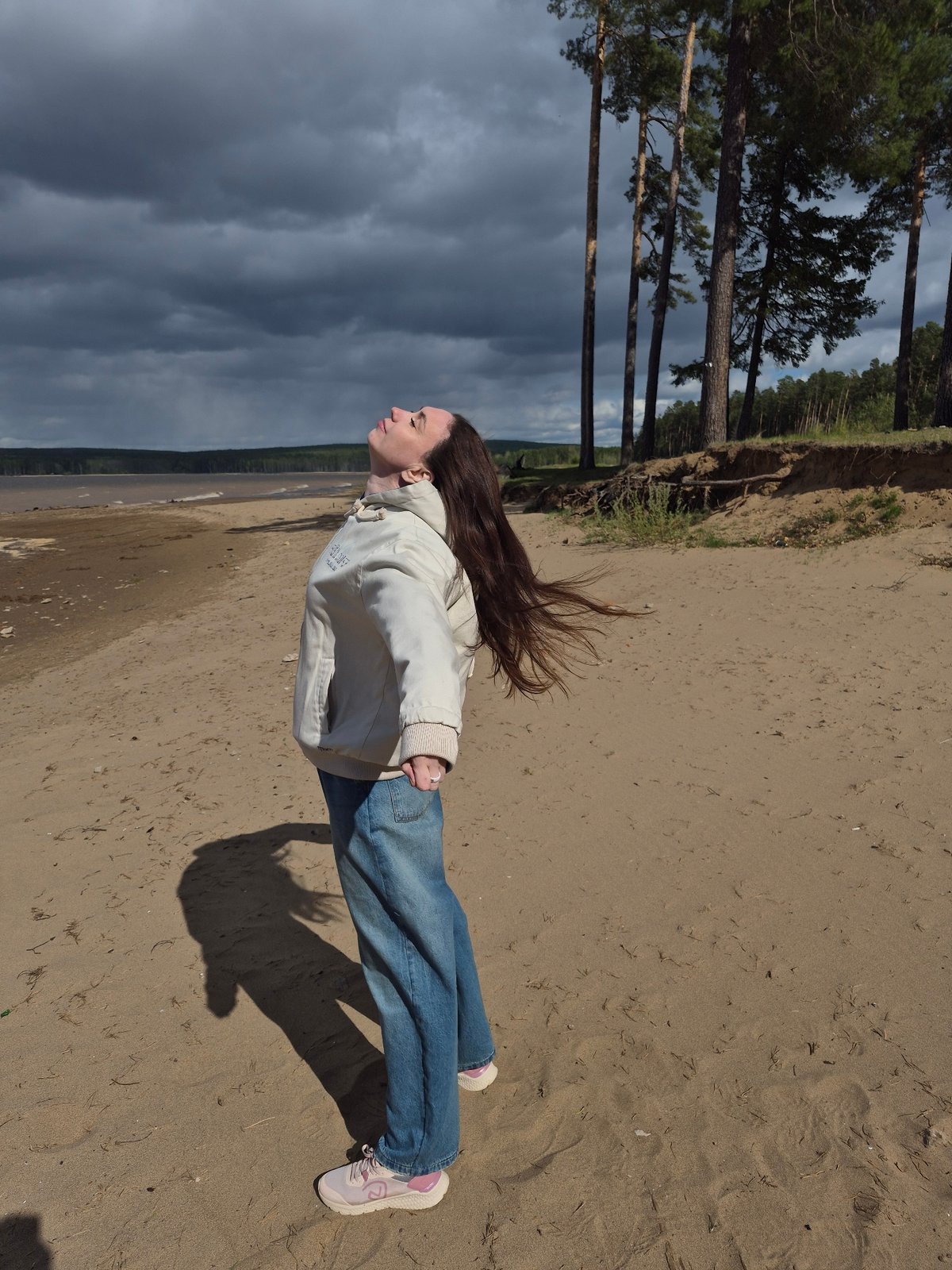 Woman enjoys brief riverside visit during changing weather in Chaikovsky