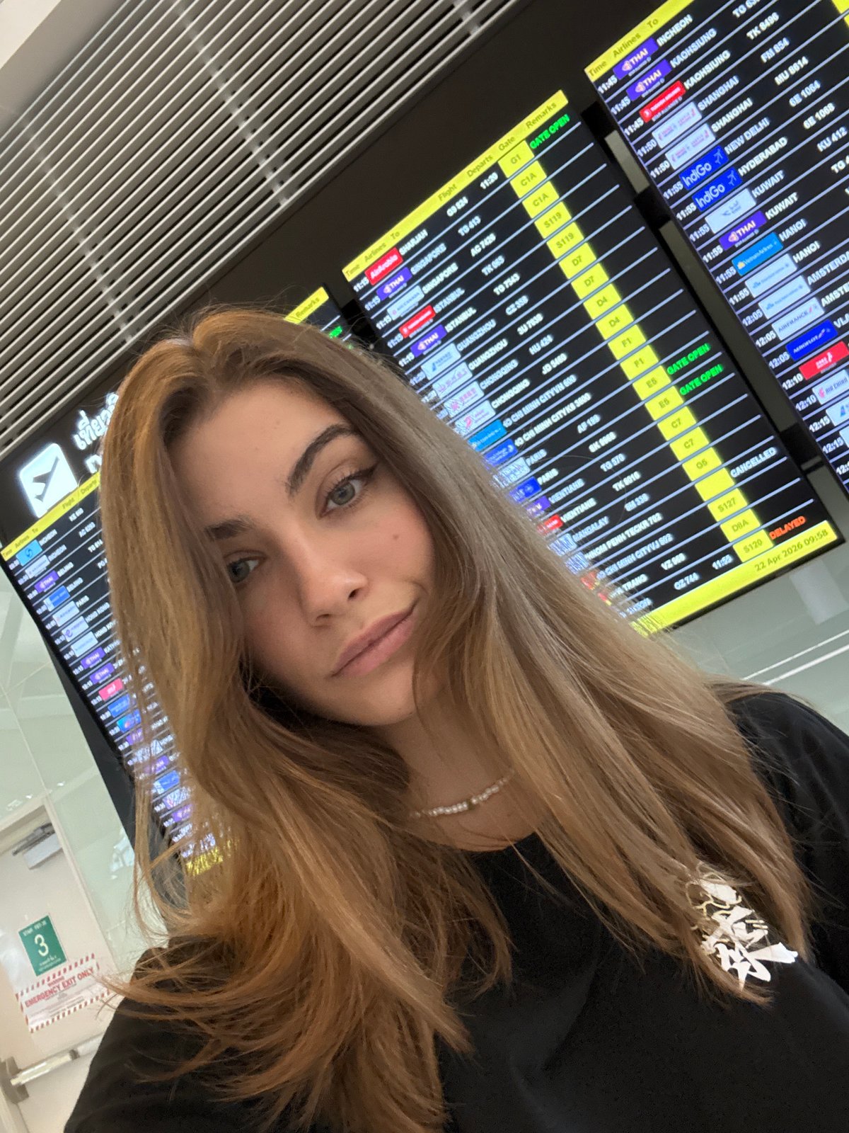 Woman poses at airport departure board in Thailand