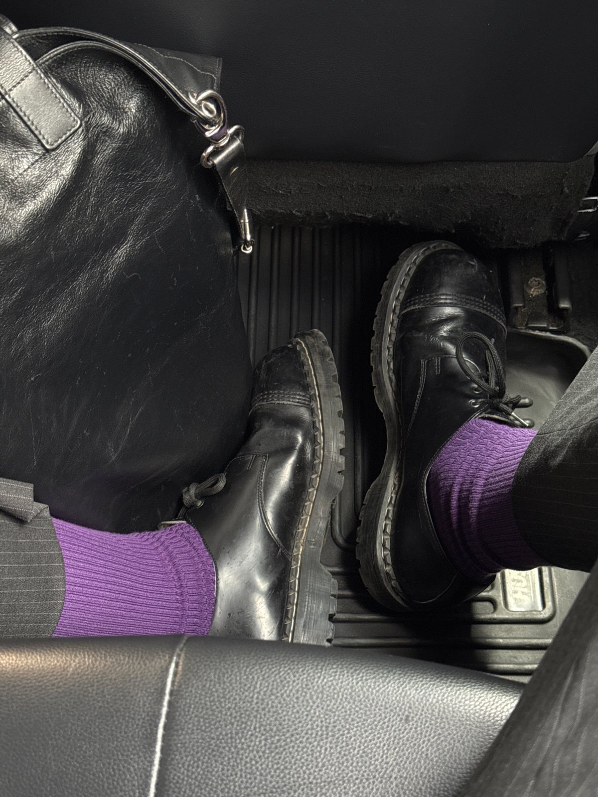 Person in pinstripe pants, purple socks photographed in NYC car