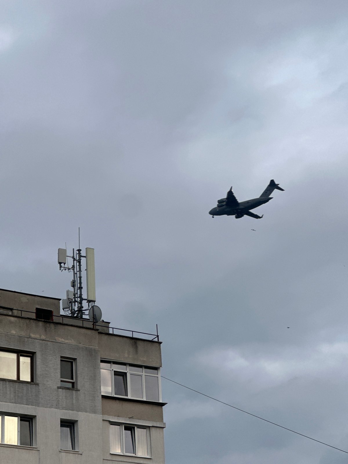 Military cargo plane spotted flying over concrete building