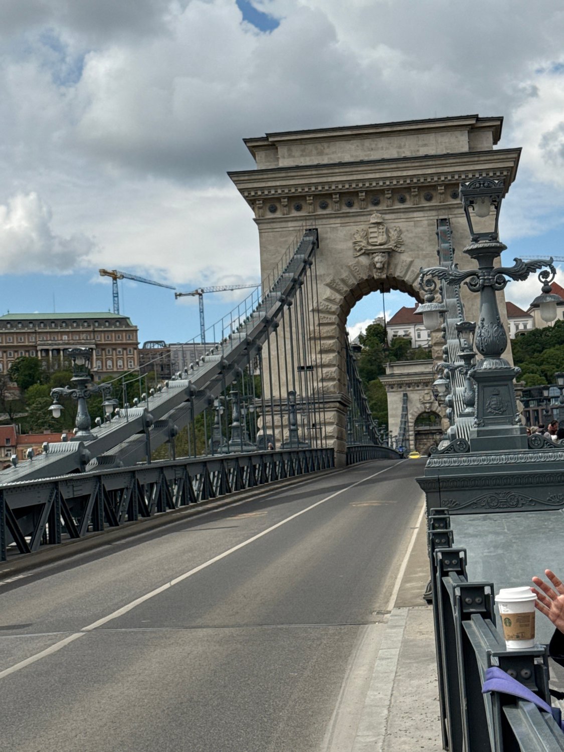 Tourist documents Chain Bridge and Budapest landmarks under cloudy skies
