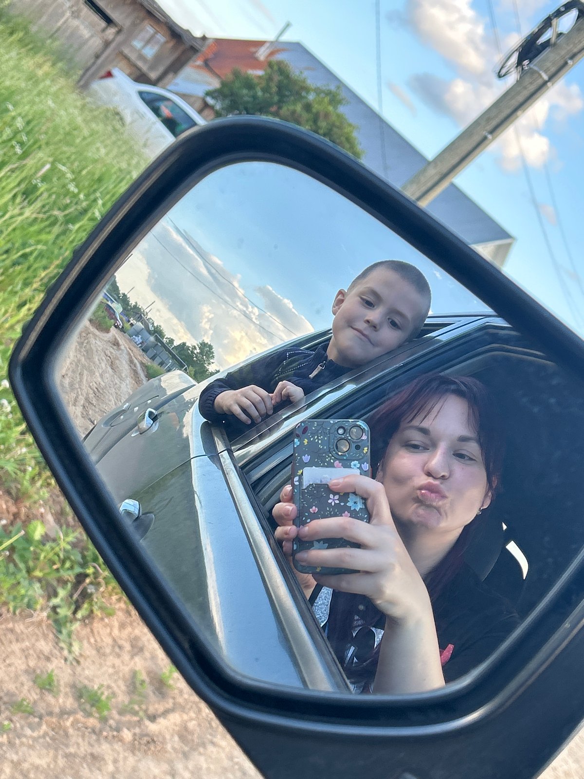 Woman and boy take leisurely car trip through Russian village
