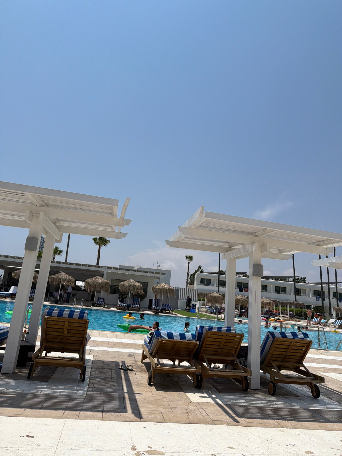 Empty lounge chairs line a sunny resort poolside