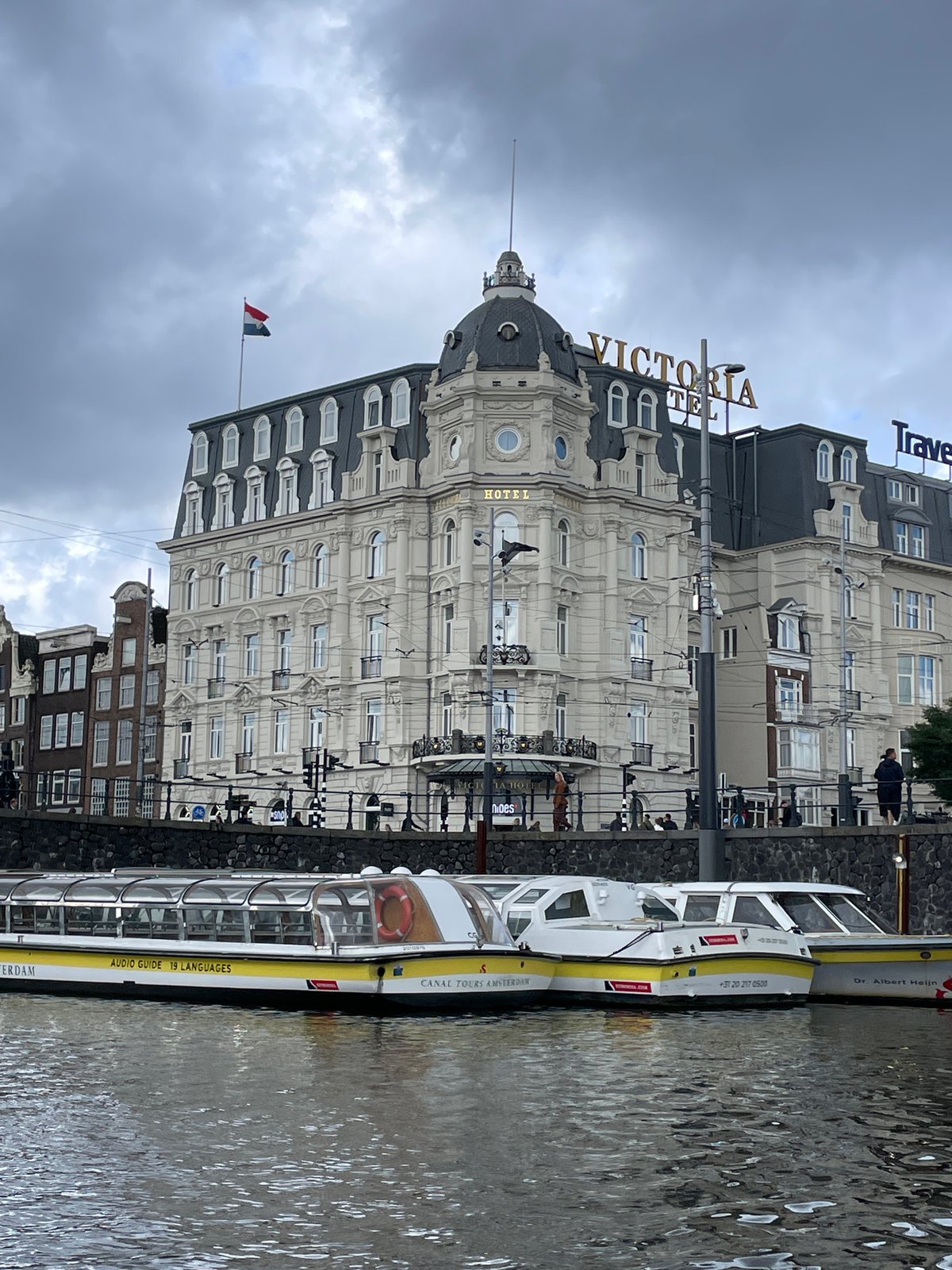 Tourist documents Amsterdam canal tour on overcast morning