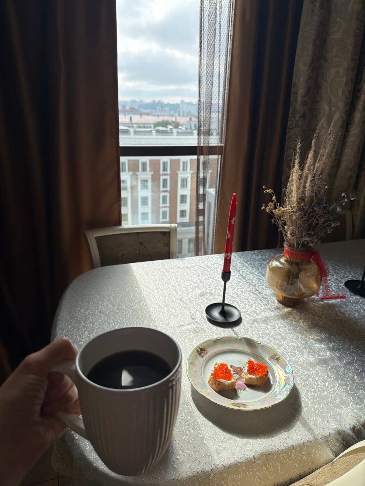 Cozy window table set with coffee, caviar bites, and candlelight