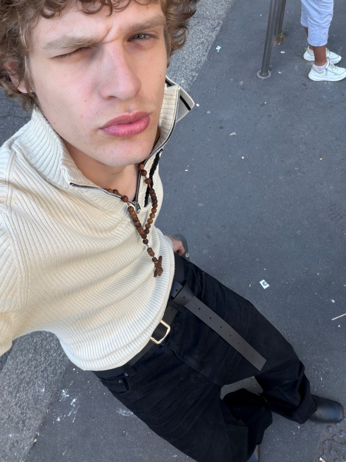 Person in cross necklace photographed from above in Milan