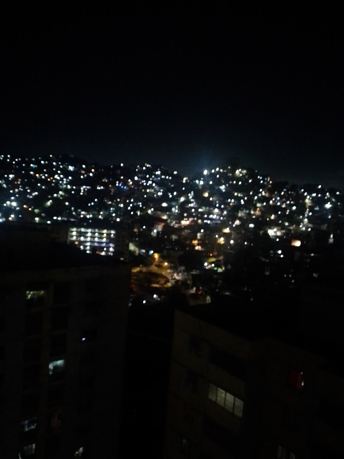 Caracas hillside neighborhoods glow across a dense nighttime skyline