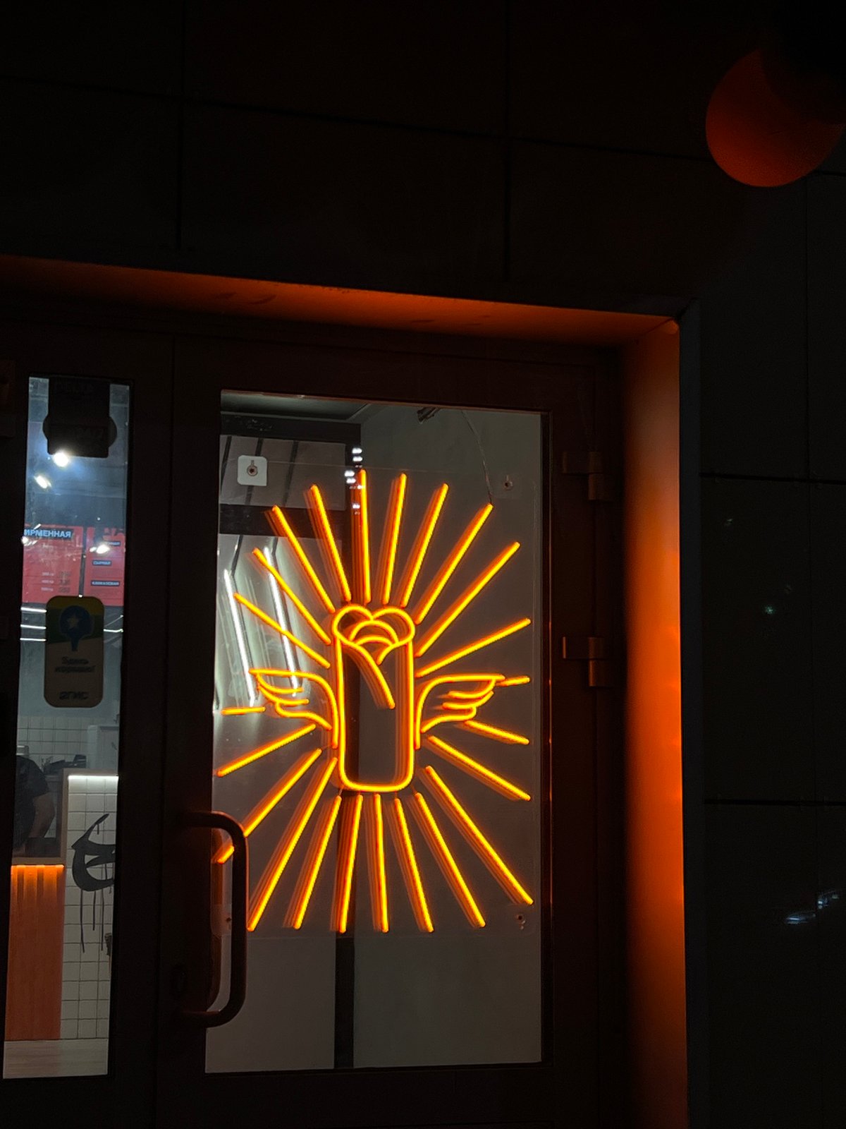 Orange neon fig sign gesture displayed in Kazan window