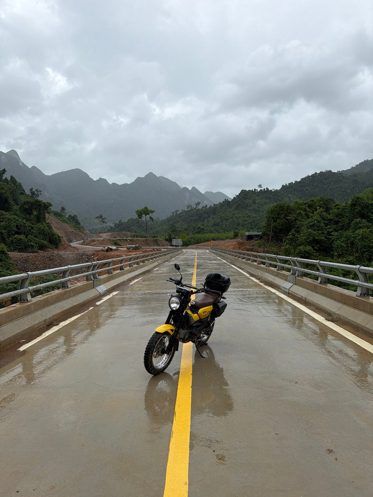 Parked motorcycle on a wet mountain bridge, Trường Sơn