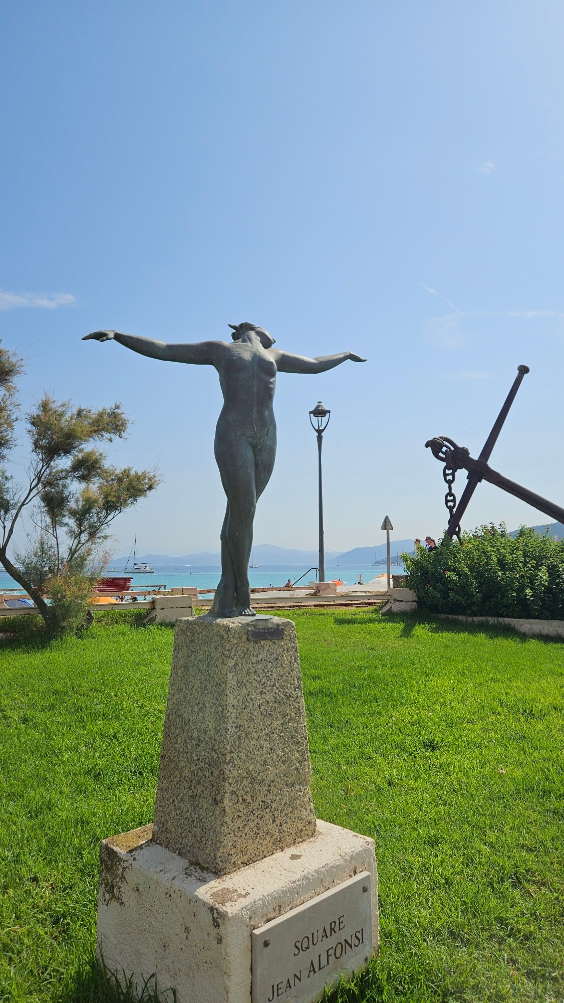 Bronze figure and rusted anchor mark L'Île-Rousse's seafront