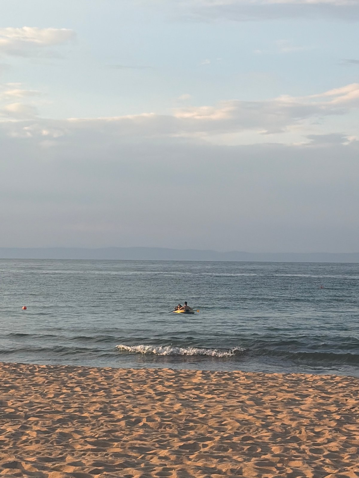 Quiet beach afternoon: wooden deck, calm water, inflatable boat.