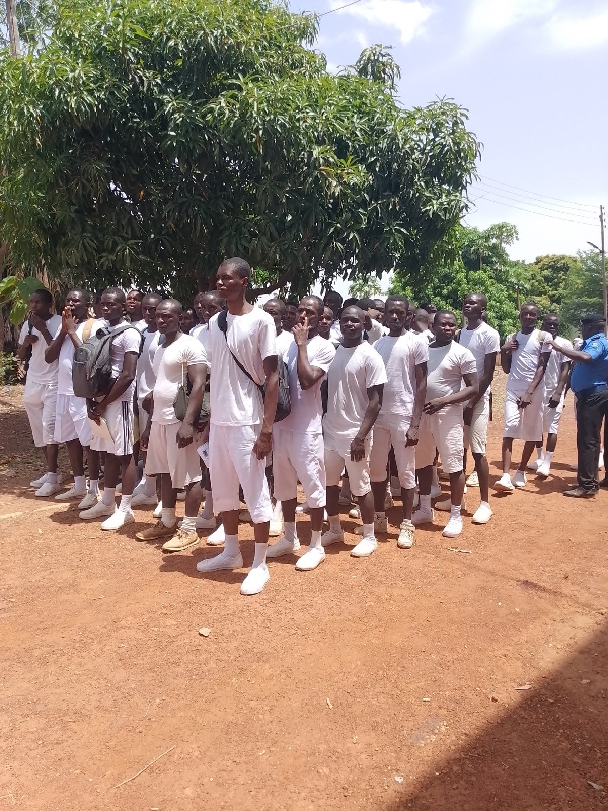 Young men in white uniforms march in formation
