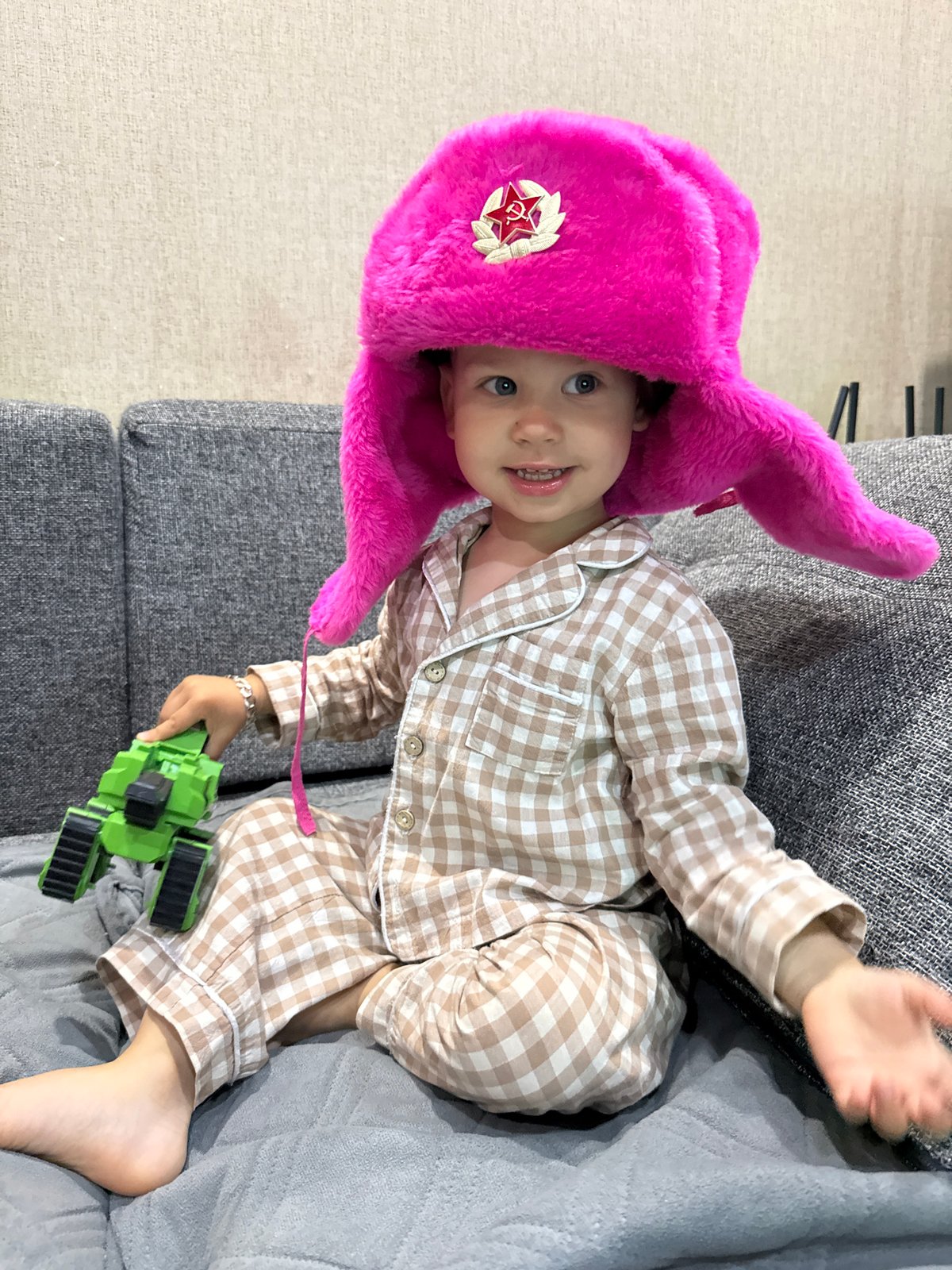 Toddler plays with toy tractor on couch in Rusanovo