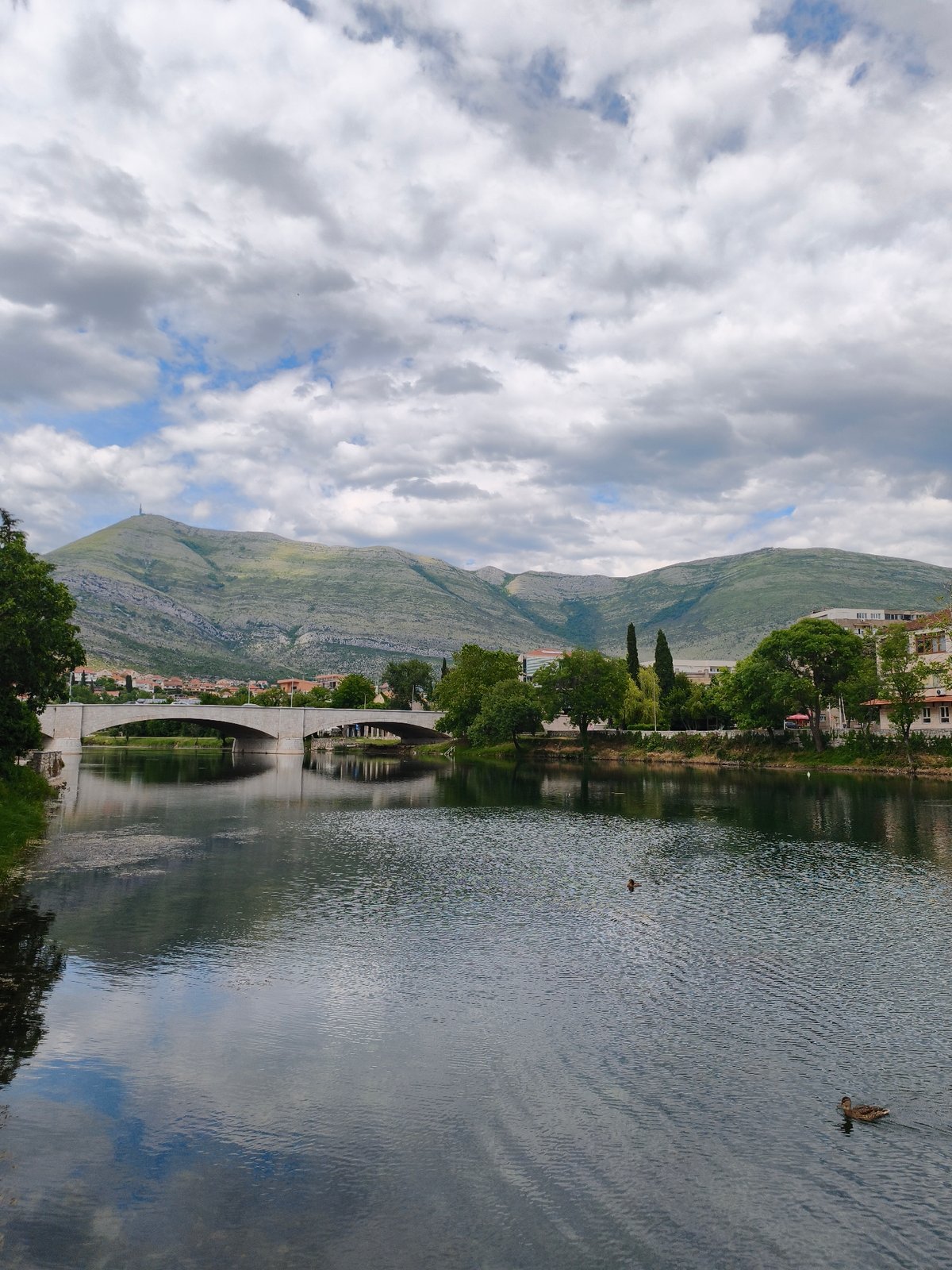 Boy feeds ducks at historic bridge in Trebinje