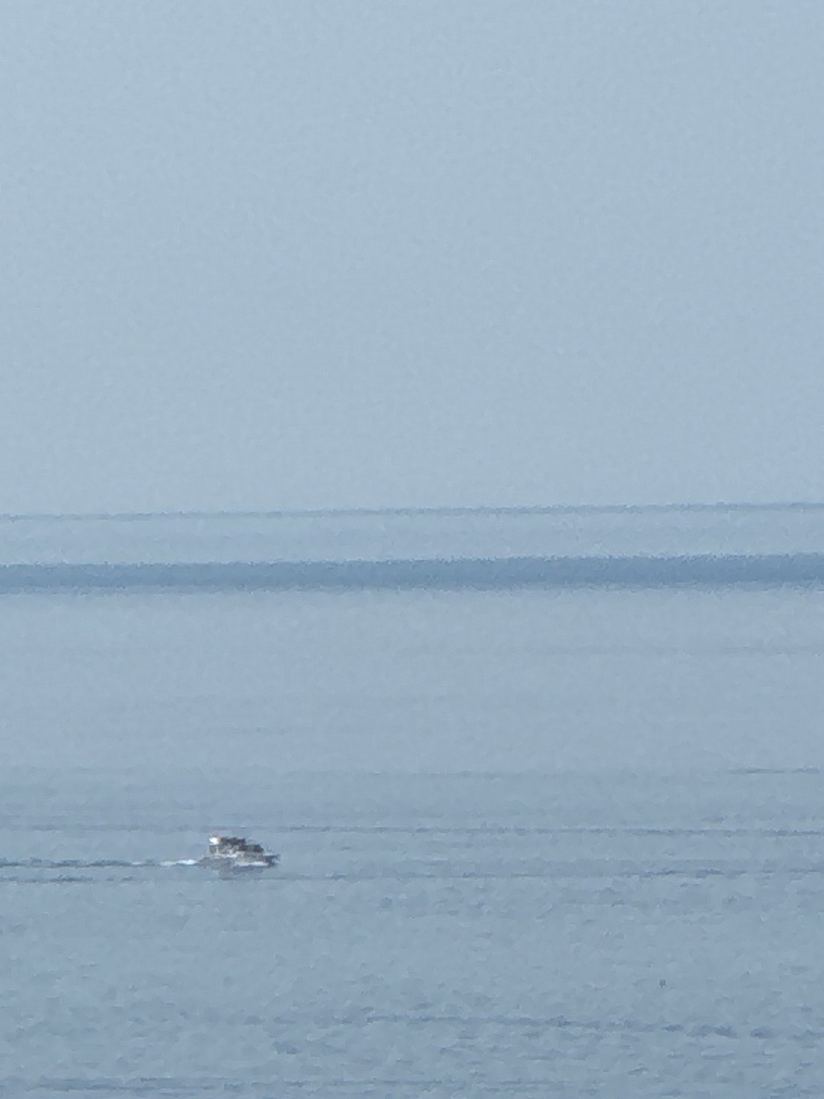 Small boat cuts through hazy morning waters off Boreti