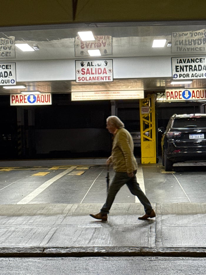 Elderly man walks toward wall in Buenos Aires parking garage