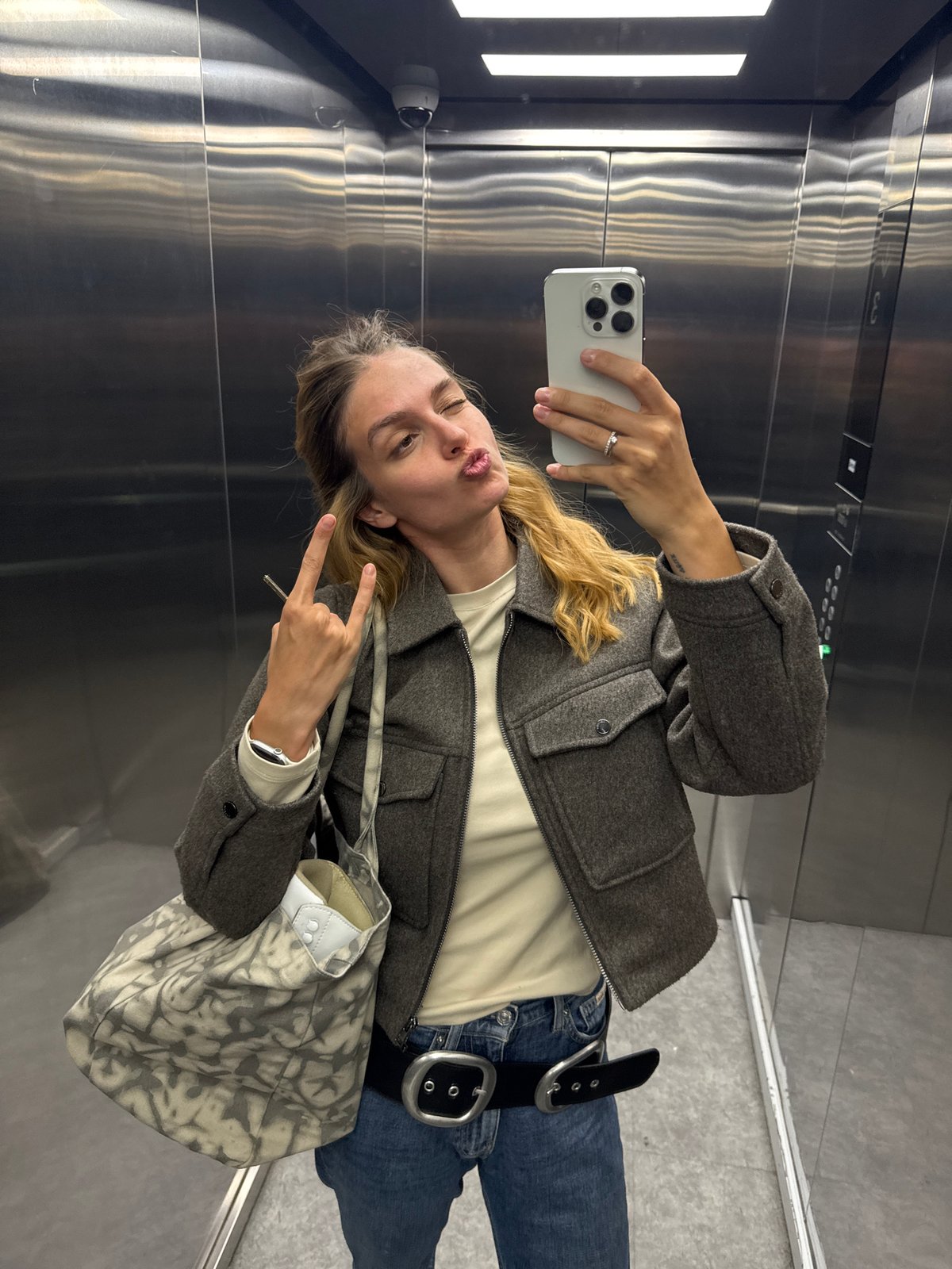 Woman takes selfie in elevator with white smartphone