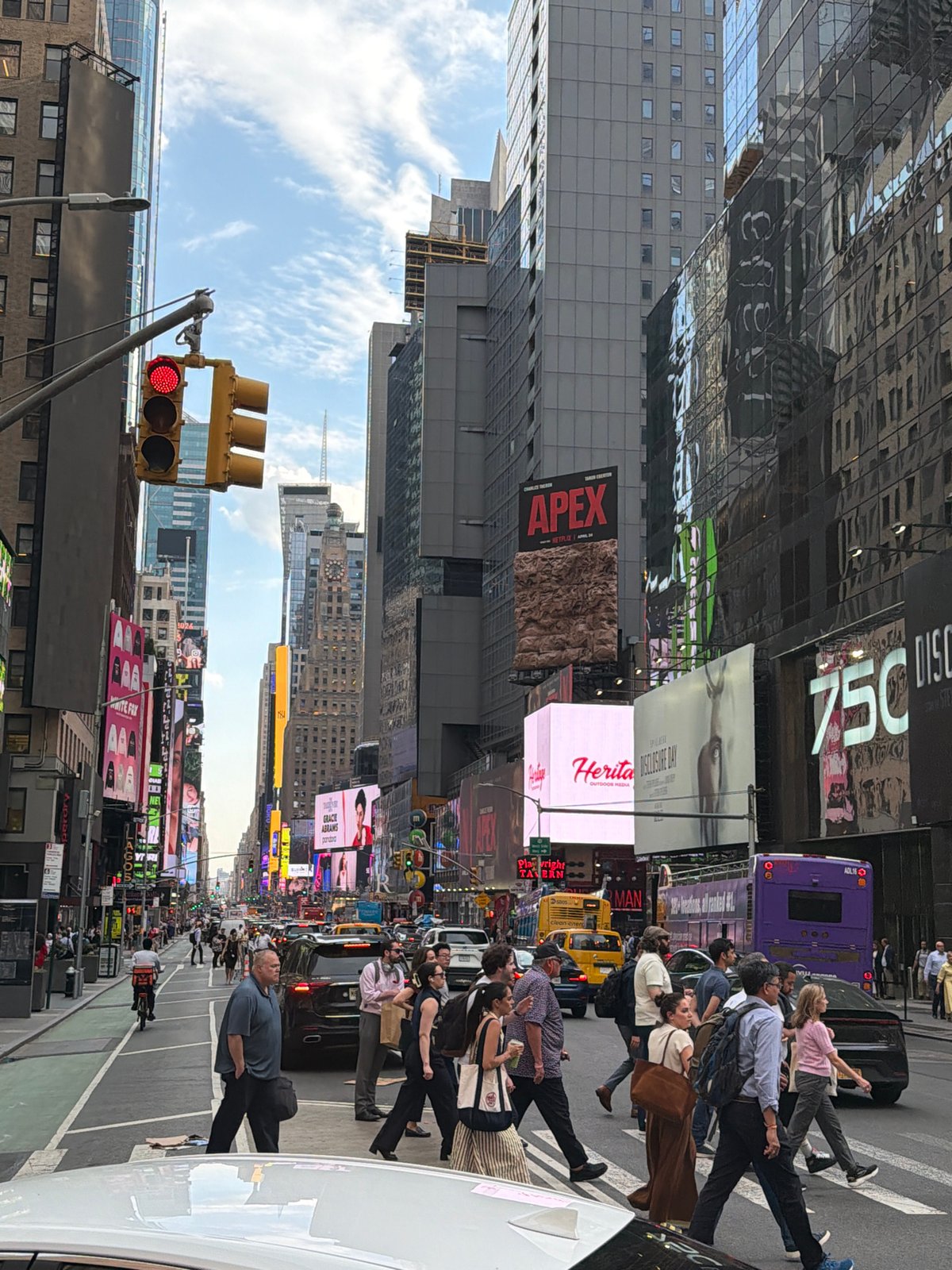 Evening crowds navigate Times Square crosswalks, selfies taken