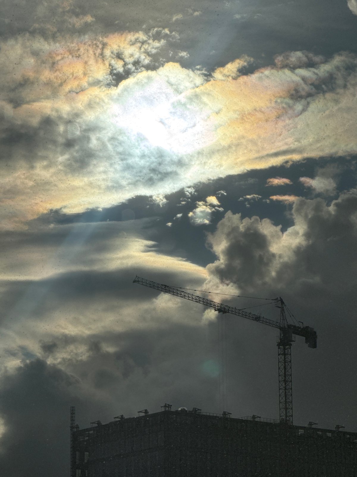 Rain moves through a city, cranes and umbrellas in the mix