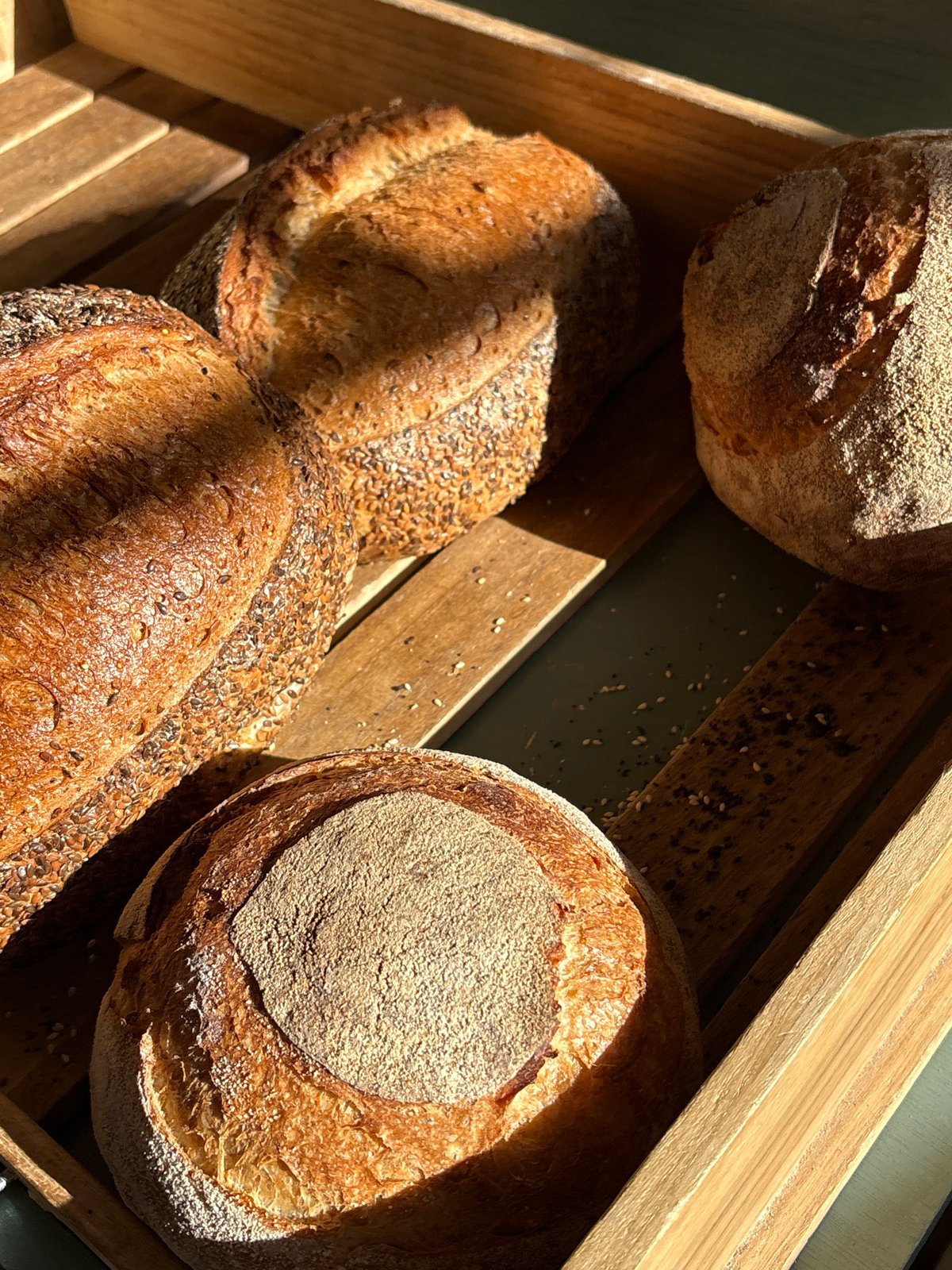 Fresh bread loaves displayed on wooden tray in London