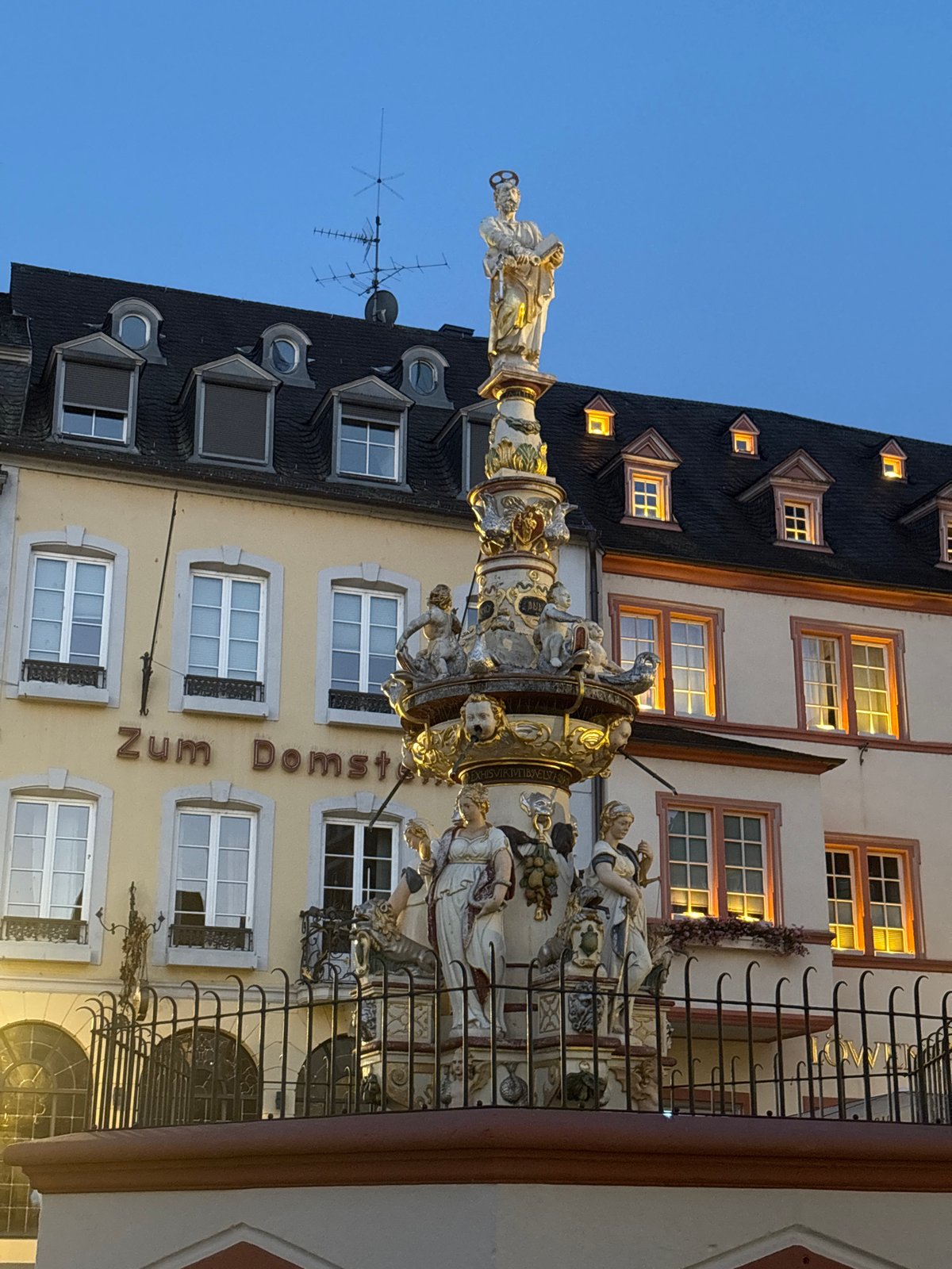 Trier's Roman fountain and cathedral at dusk
