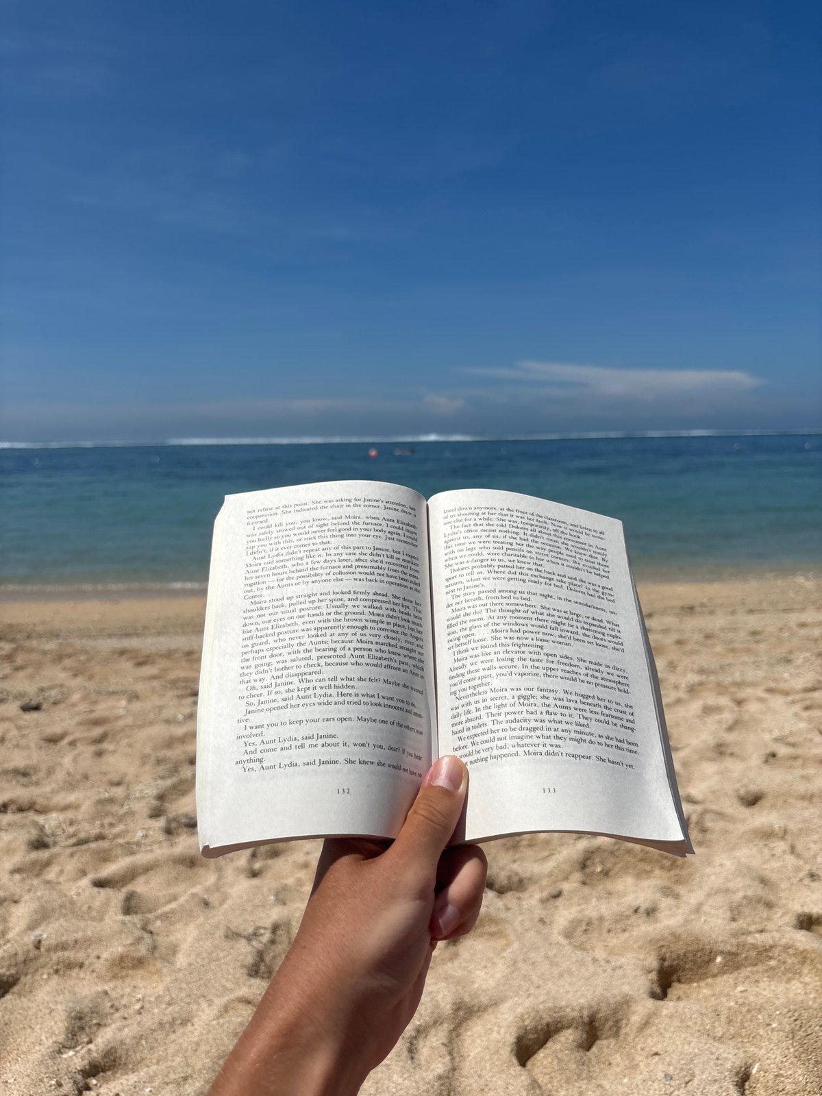 Beachgoer reads Handmaid's Tale at Kuta Selatan Indonesia beach