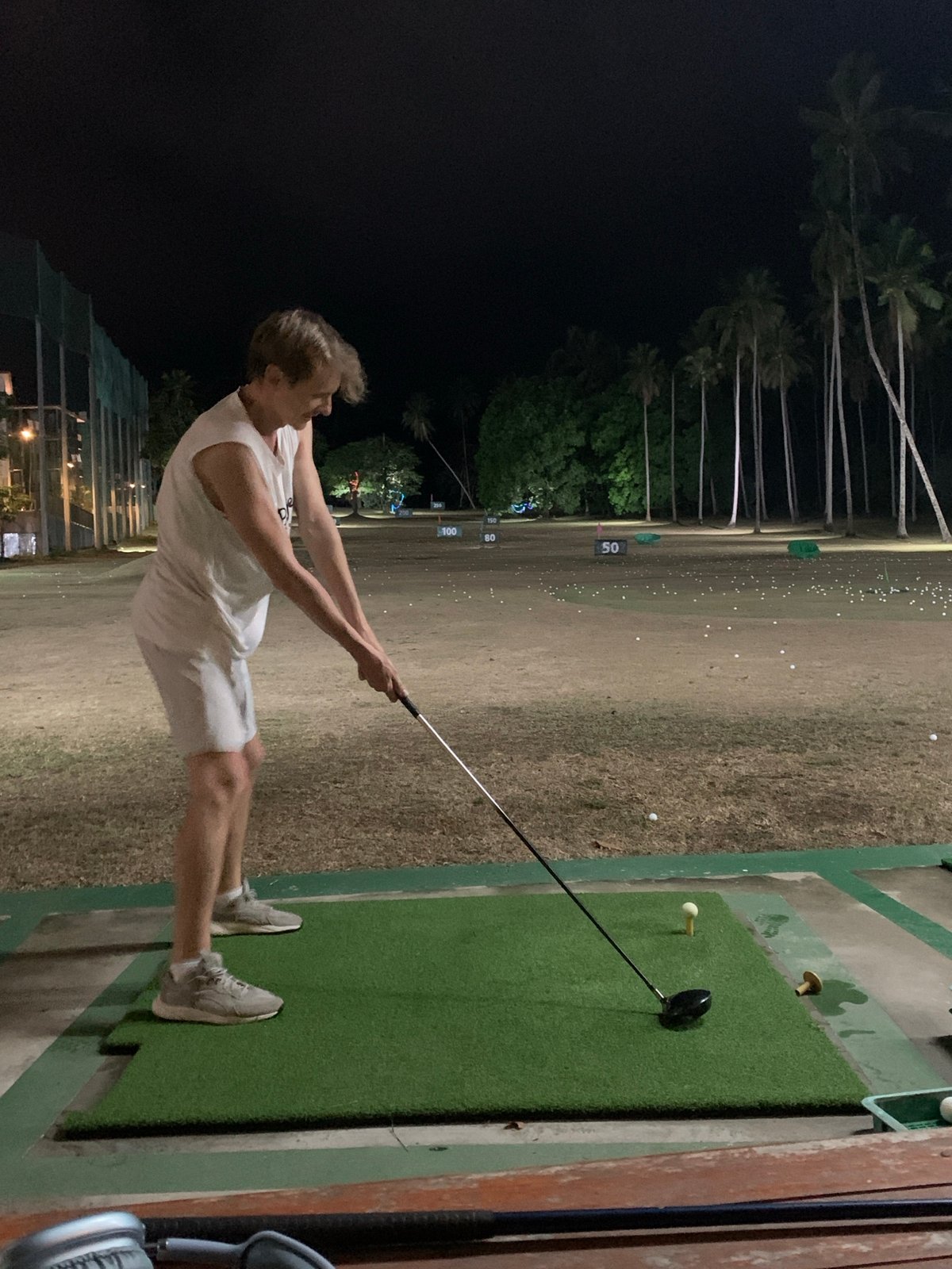 Golfer practices at night driving range in Thailand