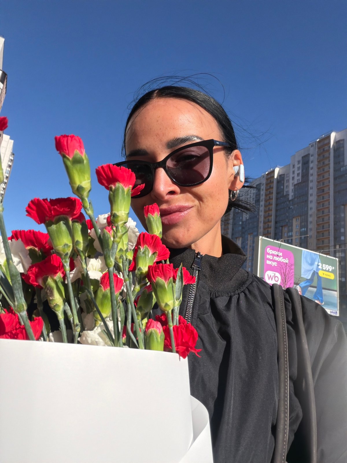 Woman records selfie with flowers on Saint Petersburg street