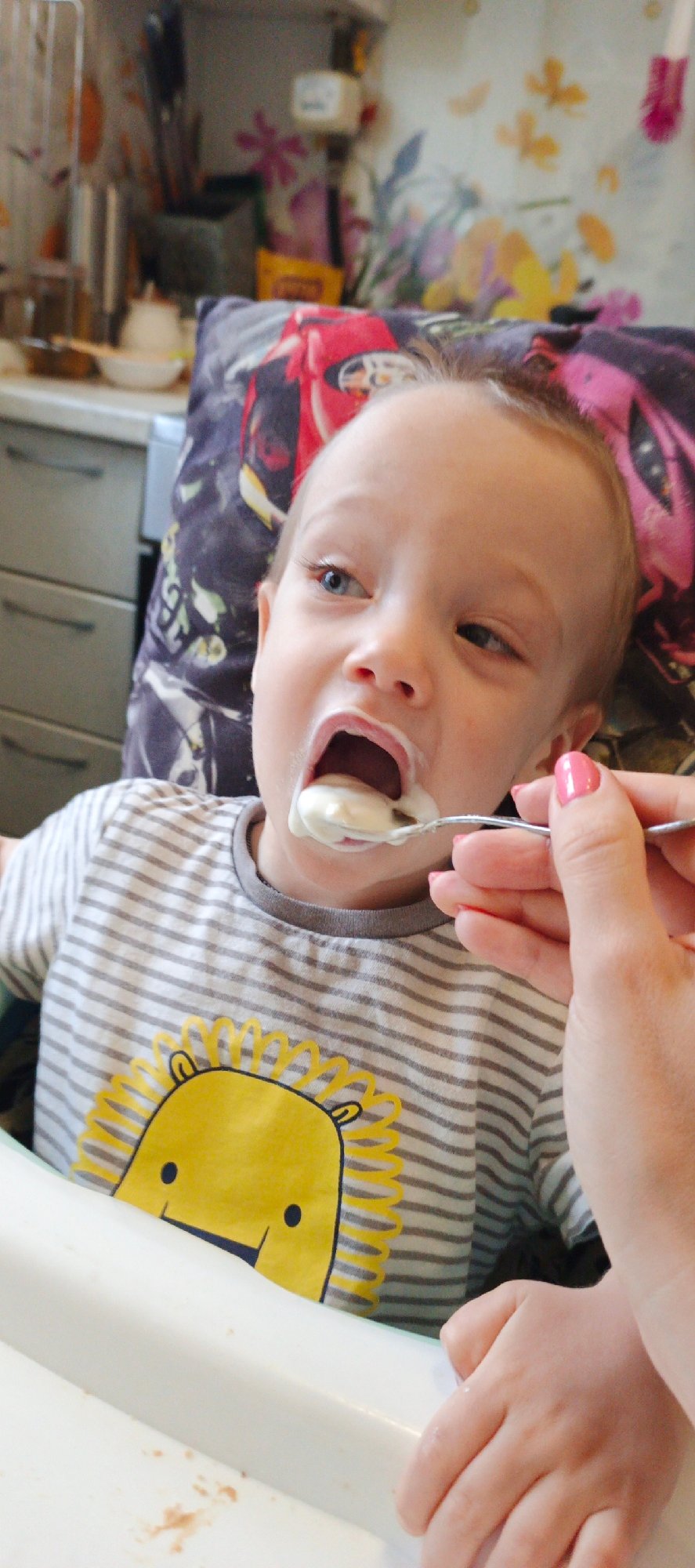 Adult feeds toddler at home in Chaikovsky, Russia