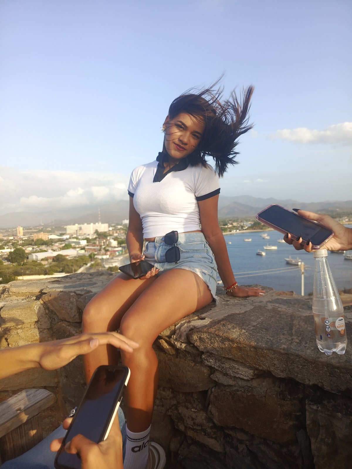Woman sits on stone wall in Venezuelan coastal town