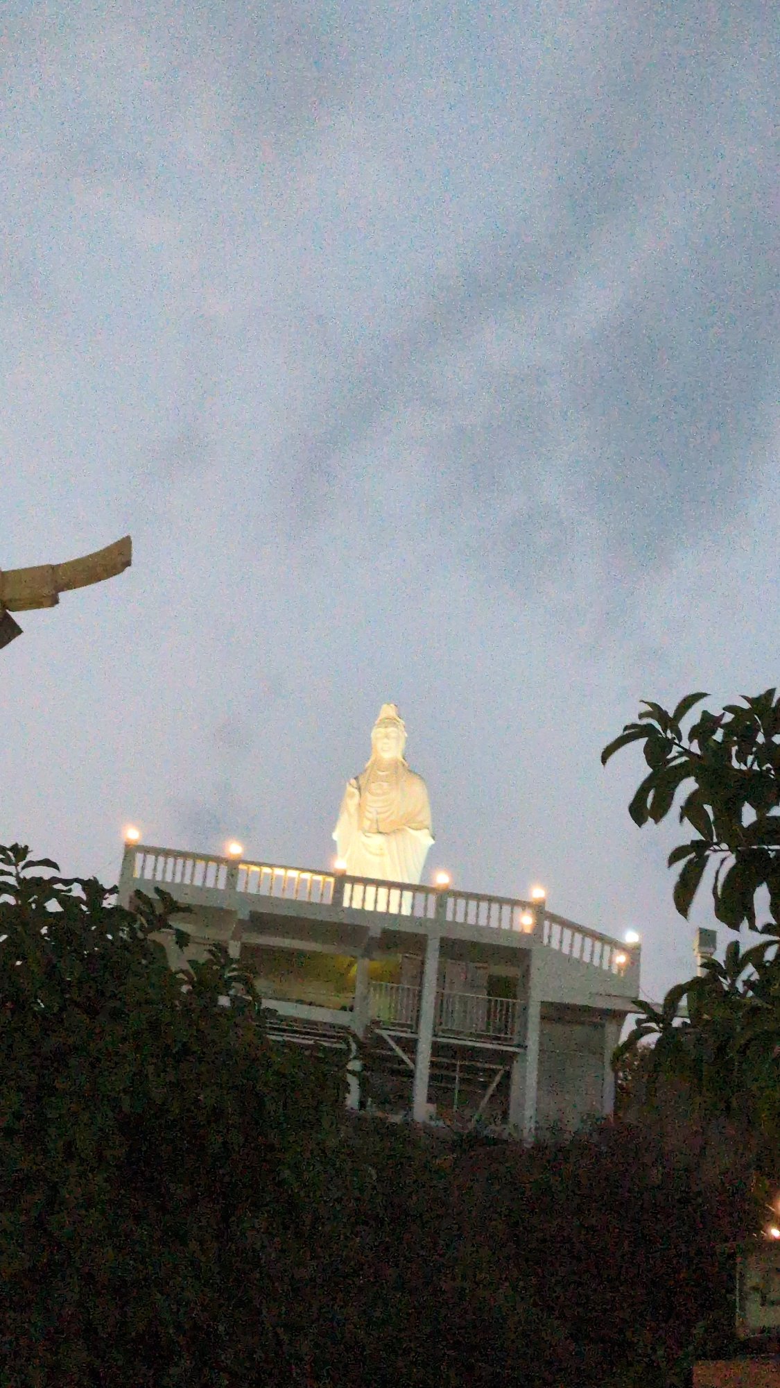 Illuminated Guan Yin statue observed on tiered structure in Vietnam