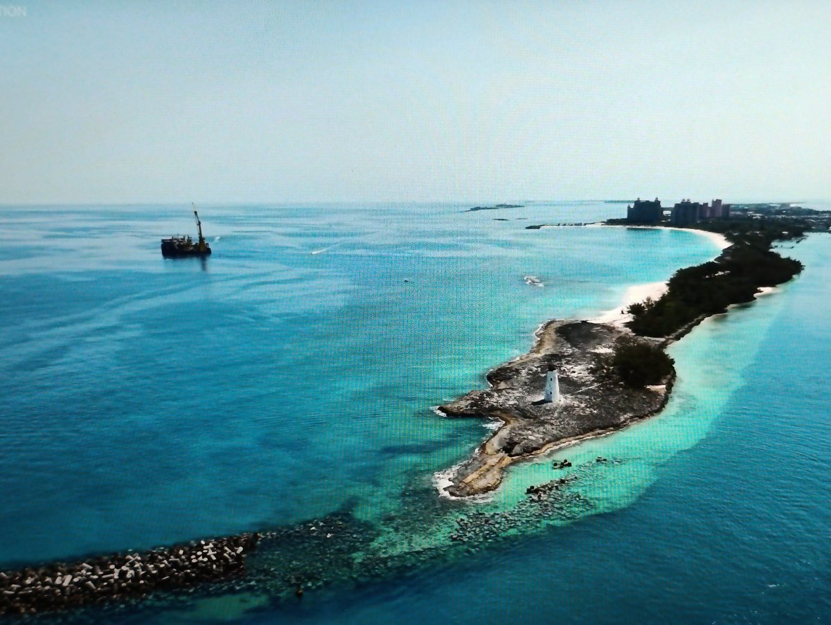 Aerial sweep of a tropical cruise port, harbor, and beachfront resort