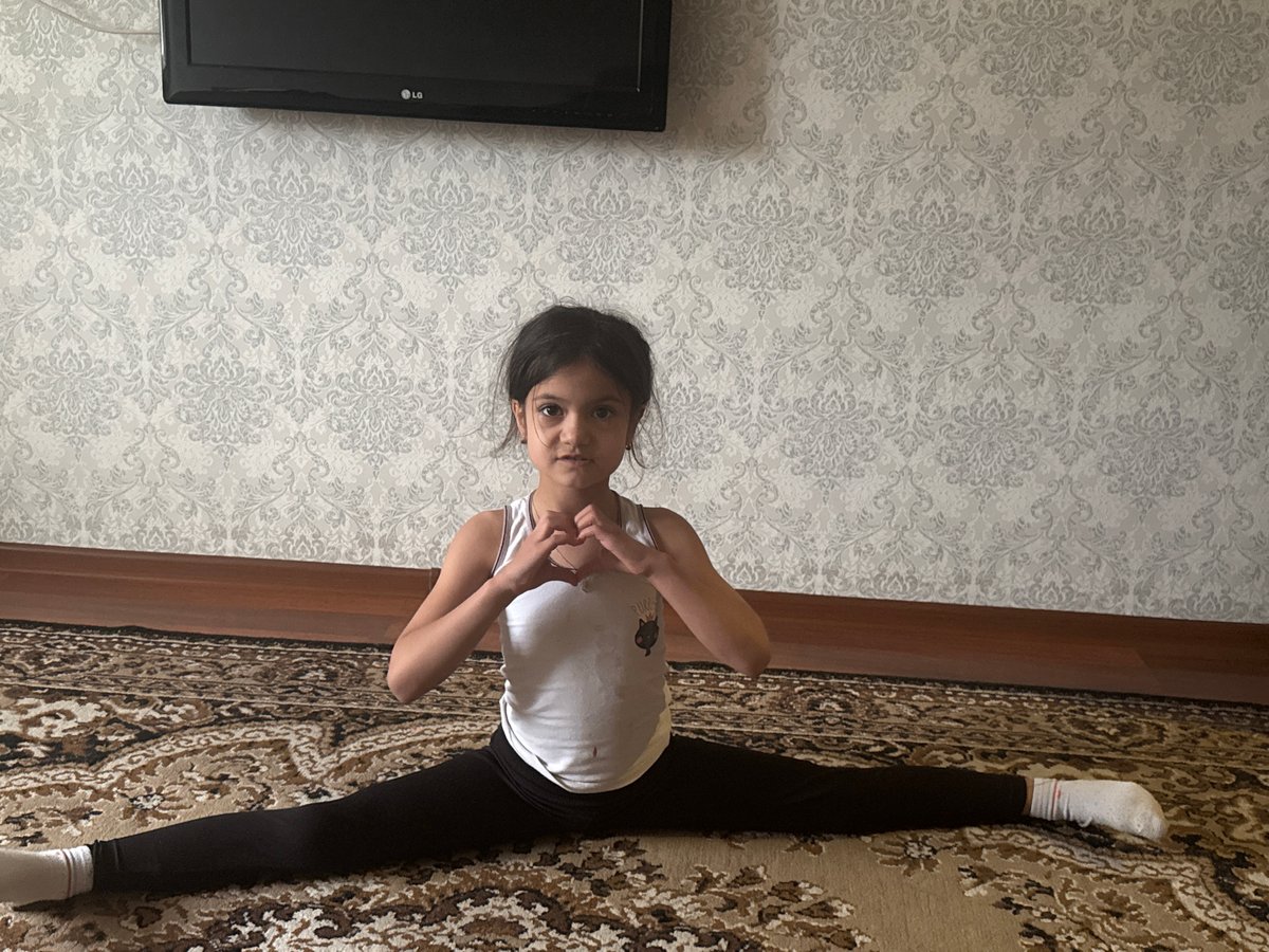 Child practices gymnastics routine indoors during overcast afternoon