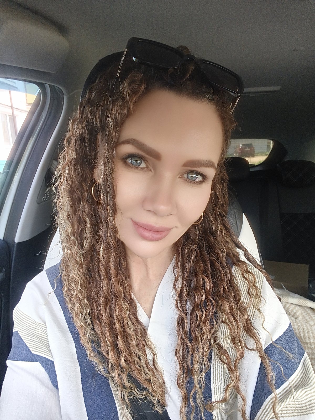 Woman with curly hair spotted in car wearing striped shirt