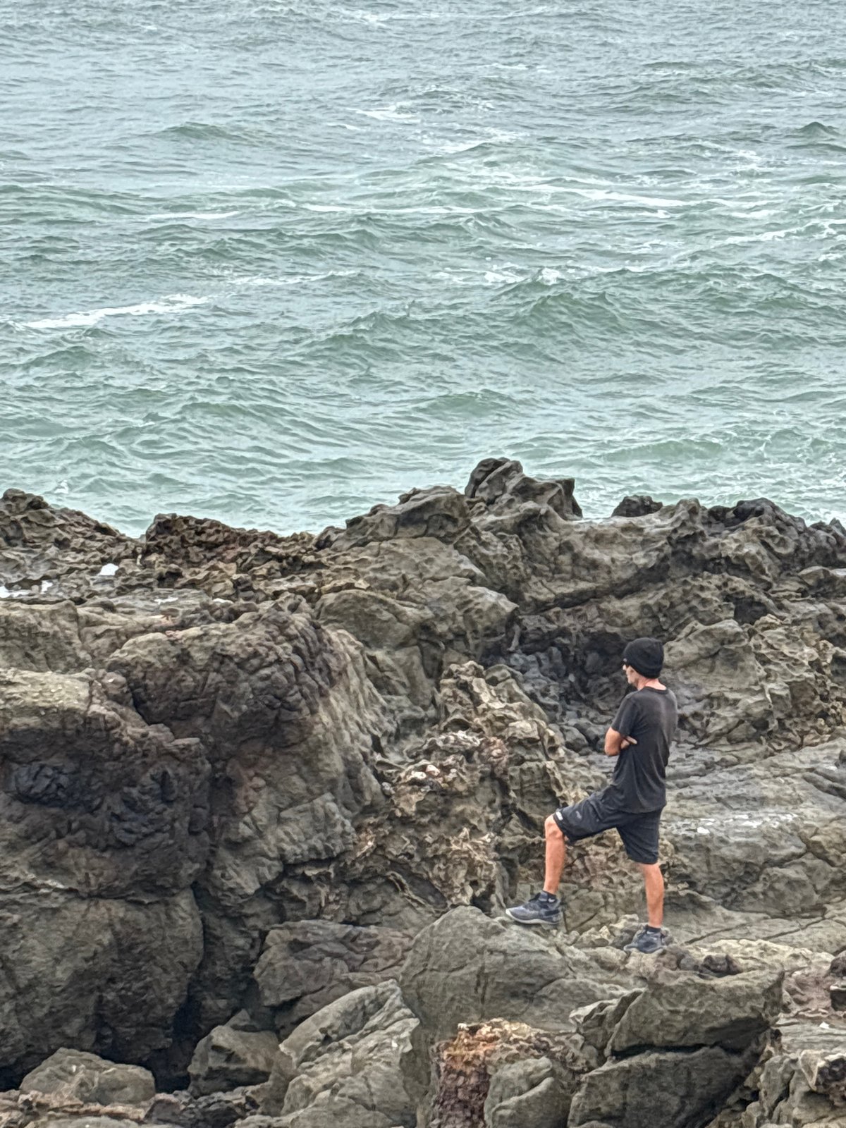 Man explores rocky coastline cliffs in Arica, Chile