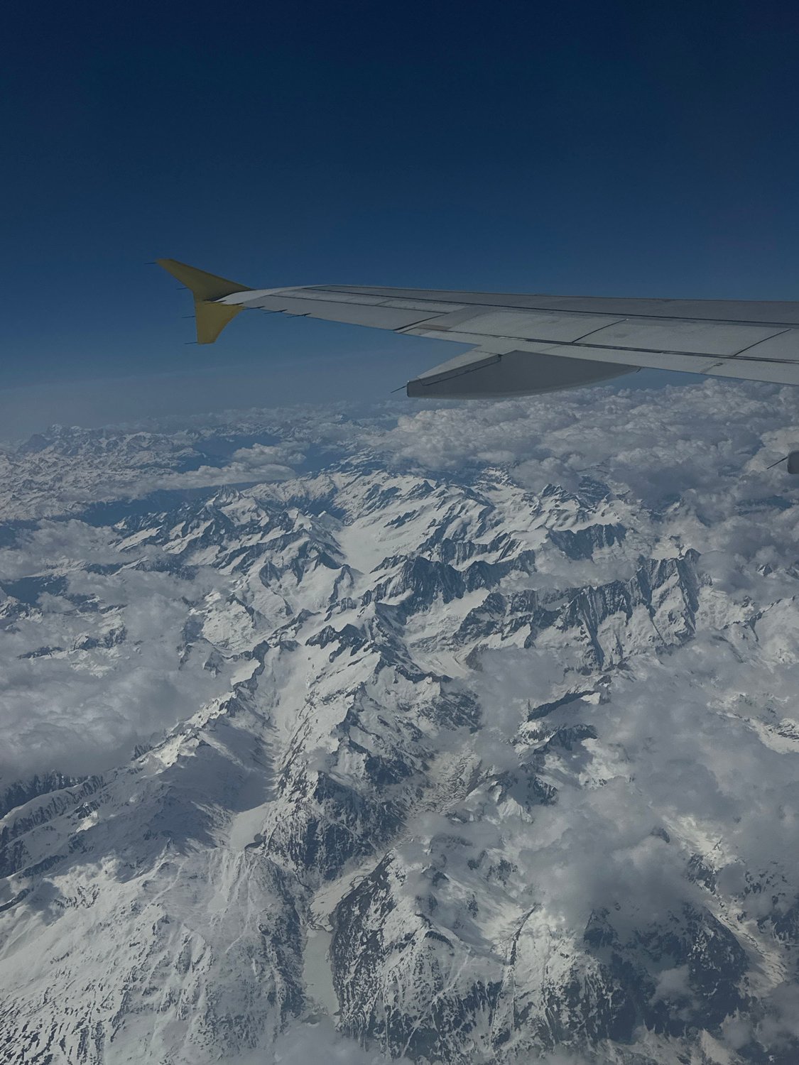 Aerial view captures aircraft wing over snowy mountains near London