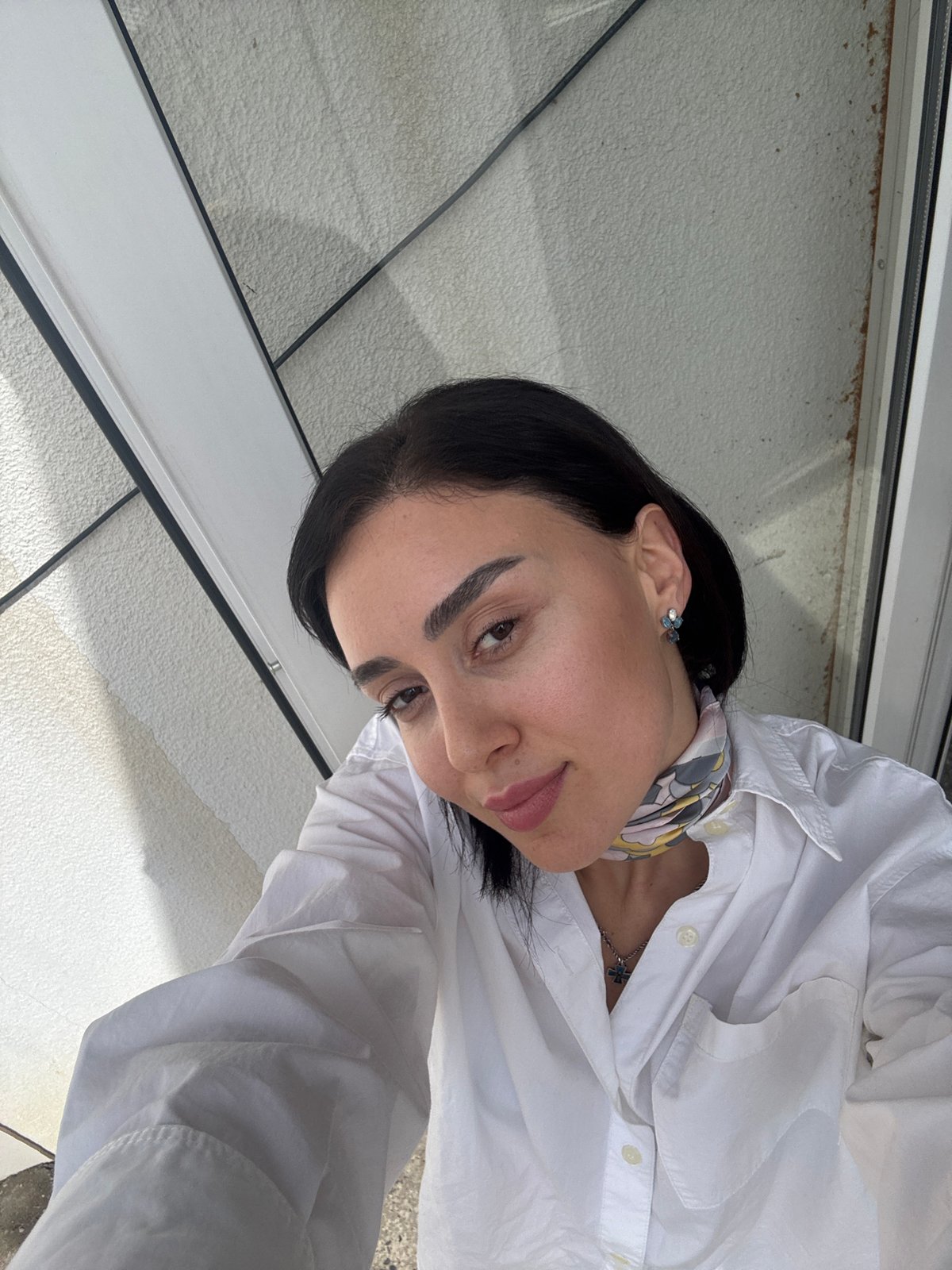 Woman takes selfies in downtown Tbilisi wearing cross necklace
