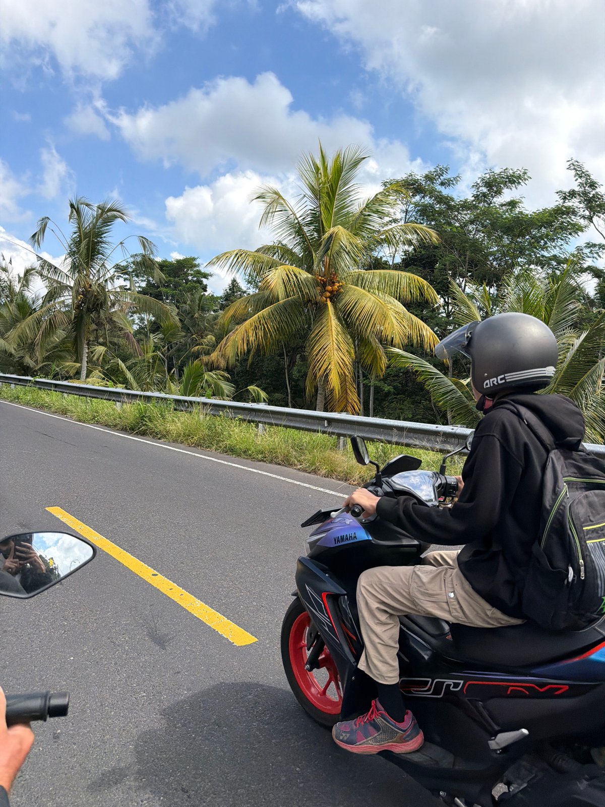 Motorcycle traffic through a lush Tampaksiring road on a cloudy morning
