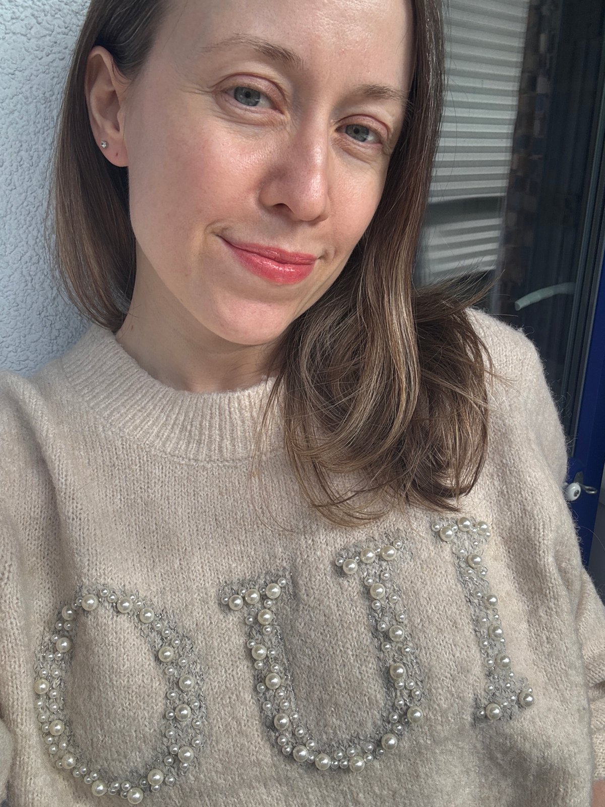 Woman in pearl-embellished sweater photographed in Kudrovo, Russia
