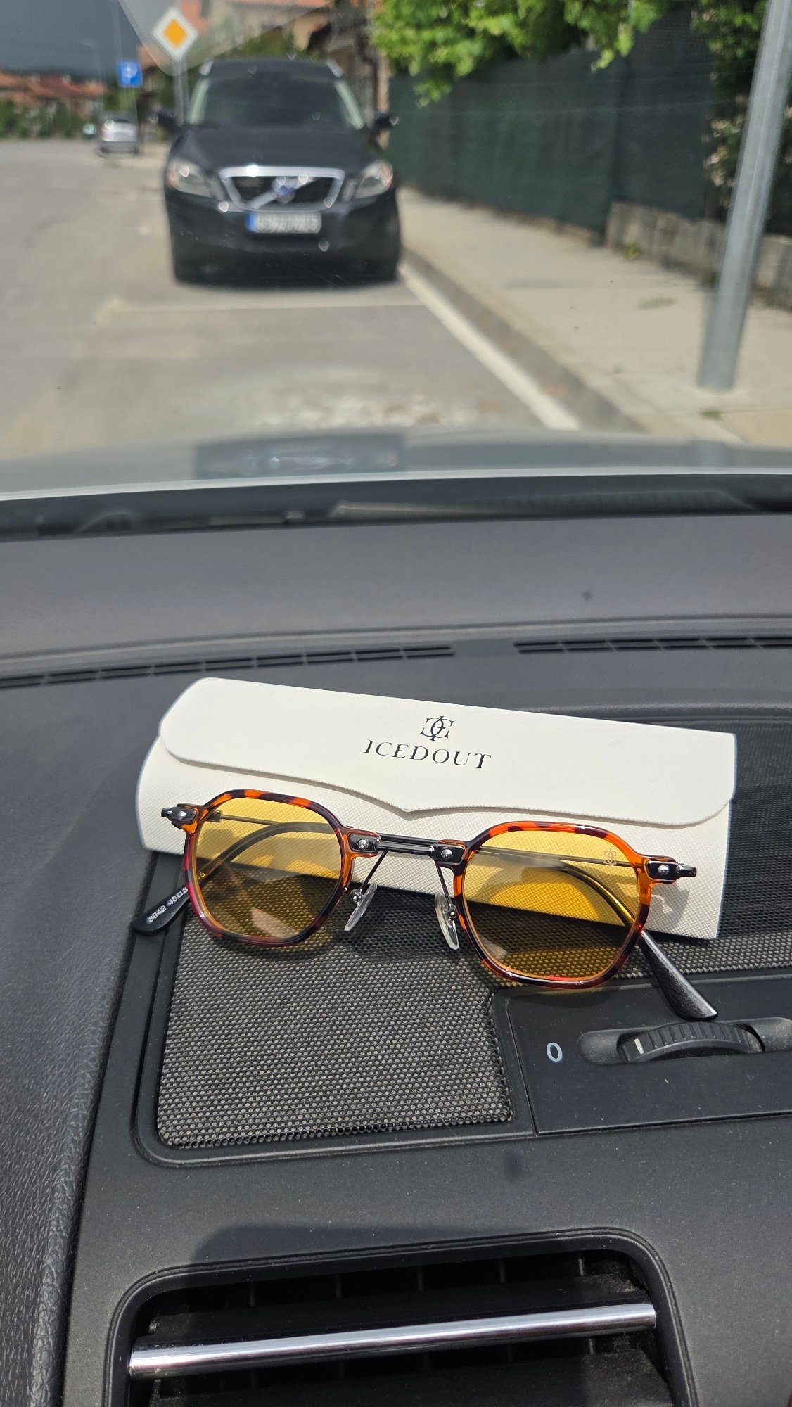 Tortoise-shell sunglasses and case on a car dashboard