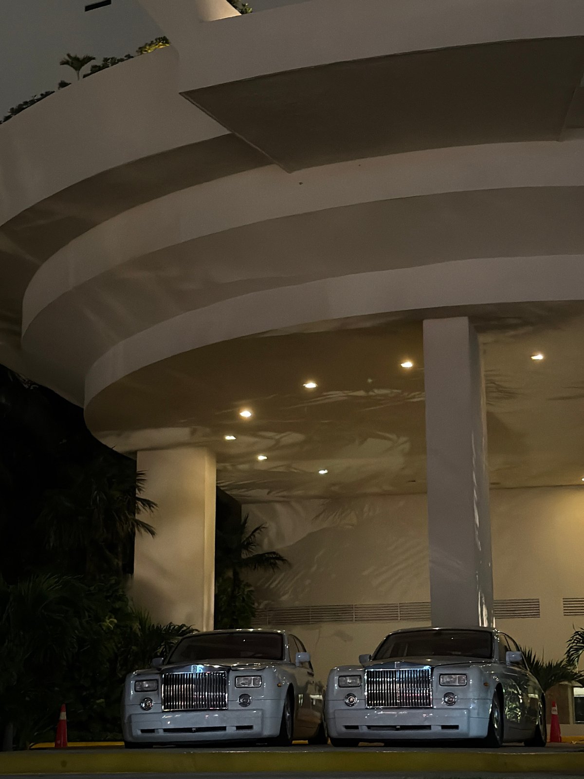 Twin white Rolls-Royces parked outside sleek Cancún venue at night