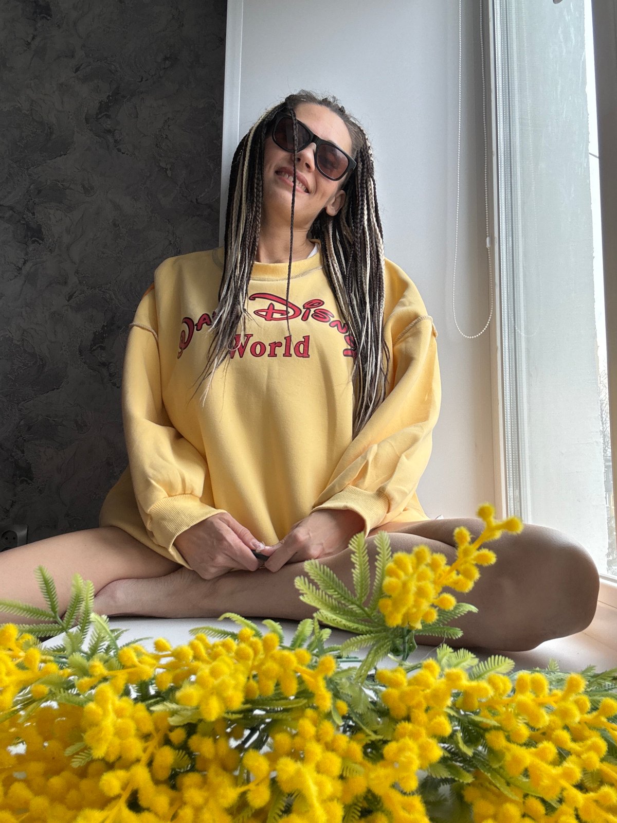Woman in Disney sweatshirt rests with flowers in Russia