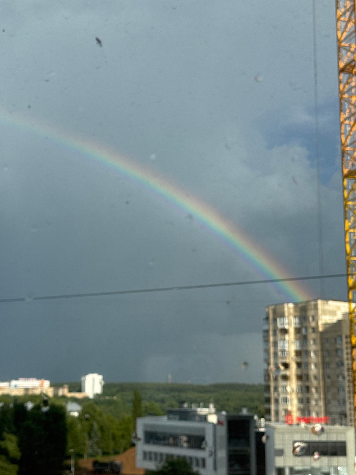 Rainbow over Ufa skyline with construction crane in frame