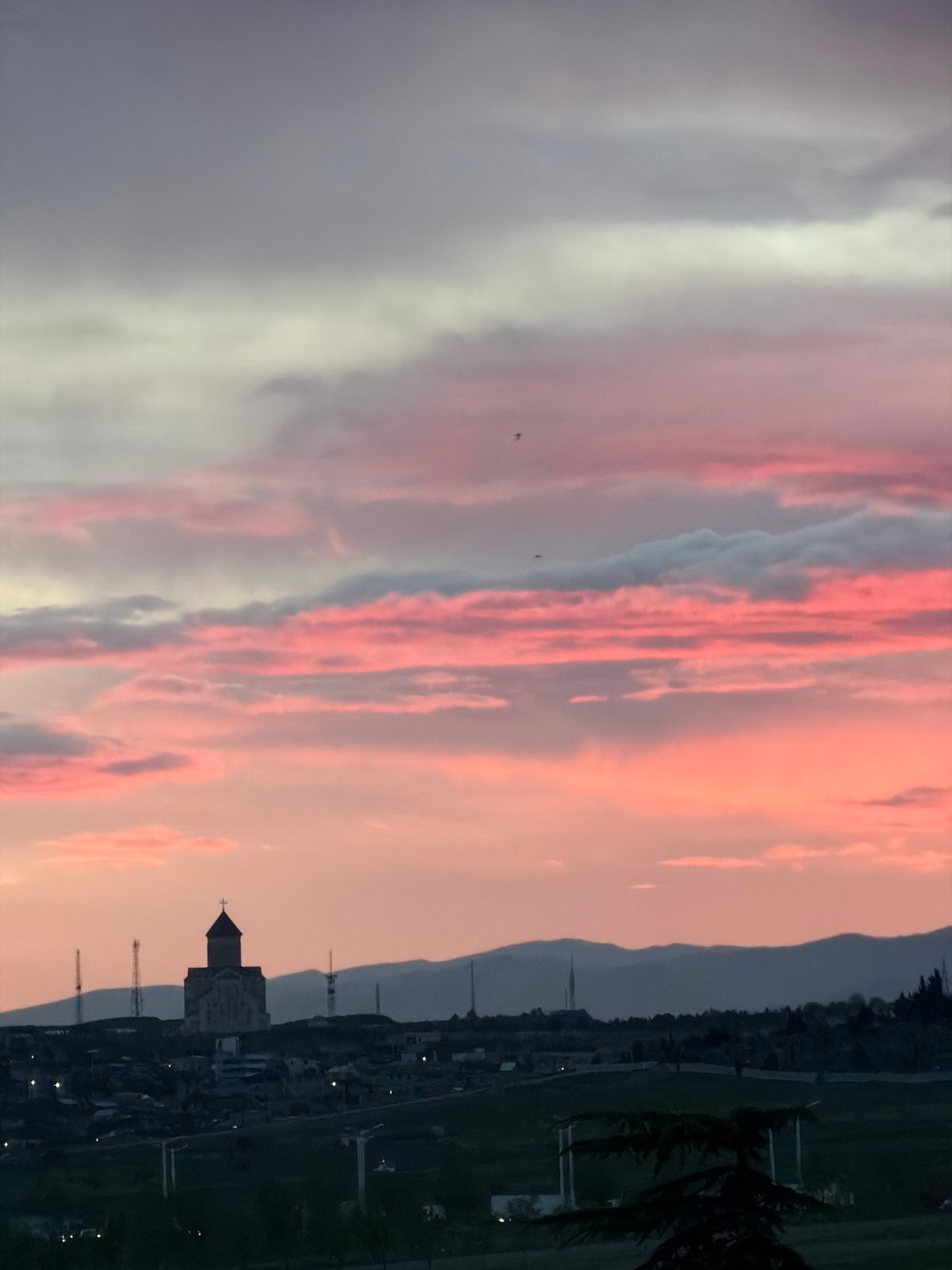 Sunset captures Tbilisi church silhouette against Georgian hills