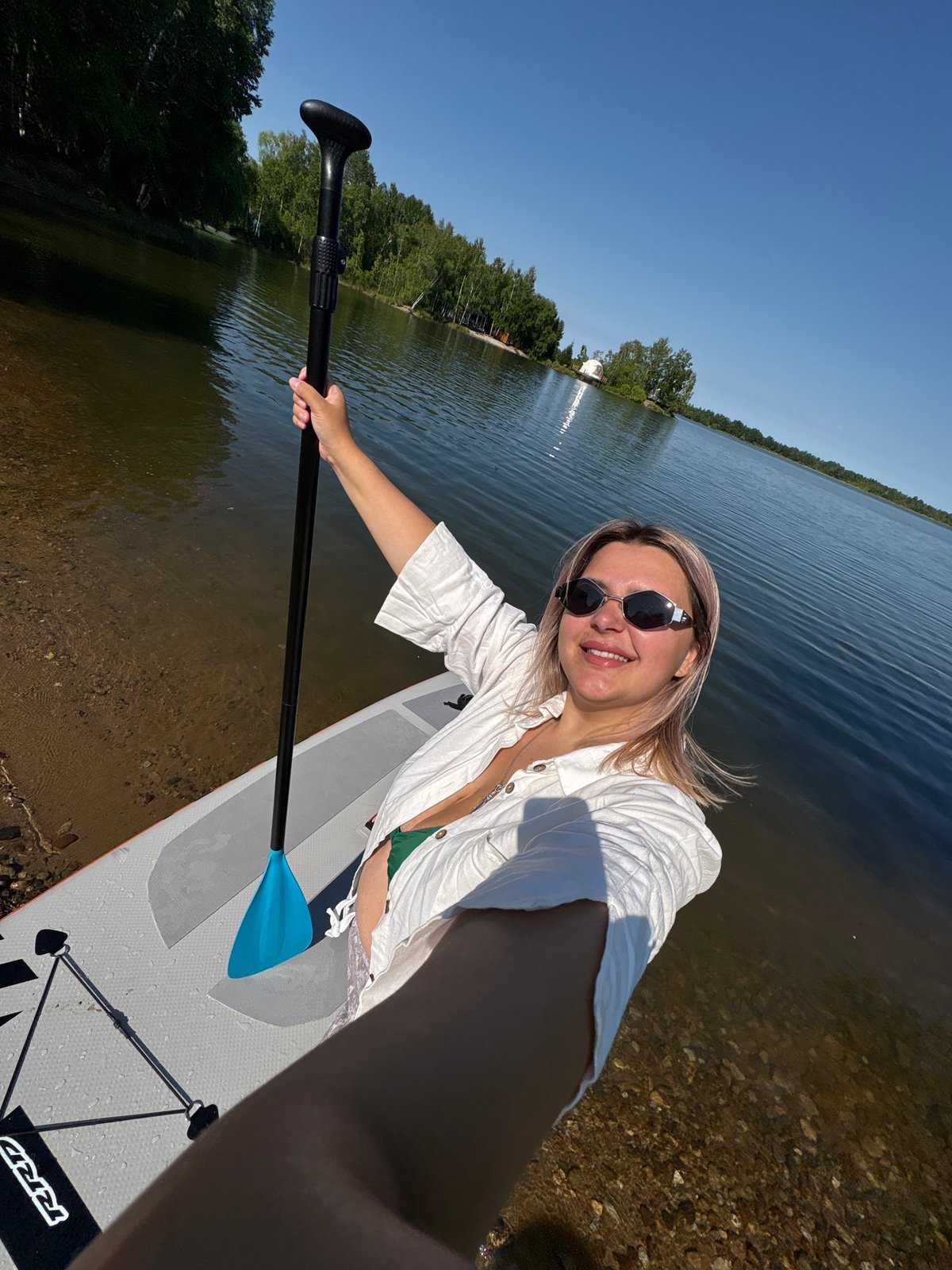 Paddleboarding a calm Russian lake on a clear summer morning