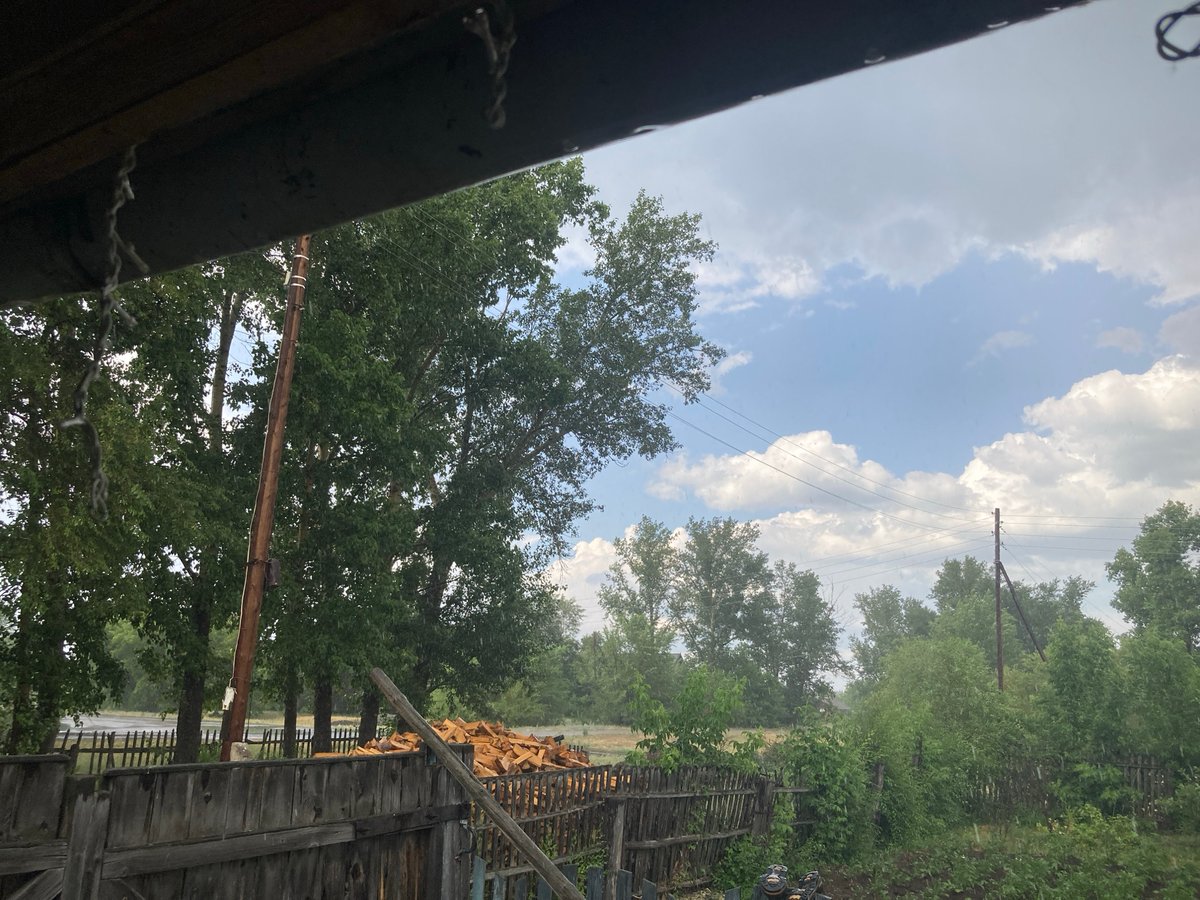 Rural Siberian village under a shifting, stormy summer sky