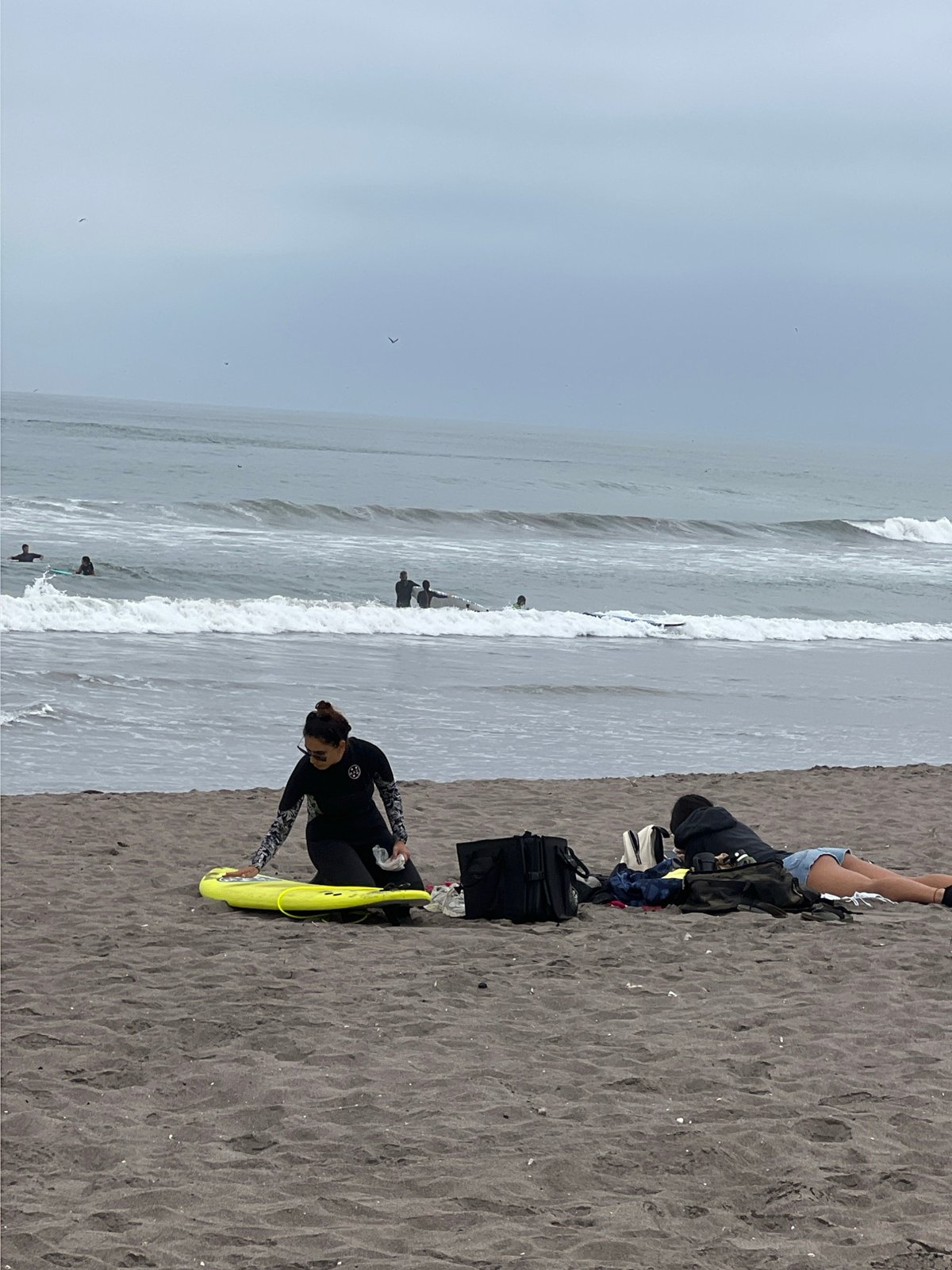 Overcast afternoon brings surfers and families to Arica beach